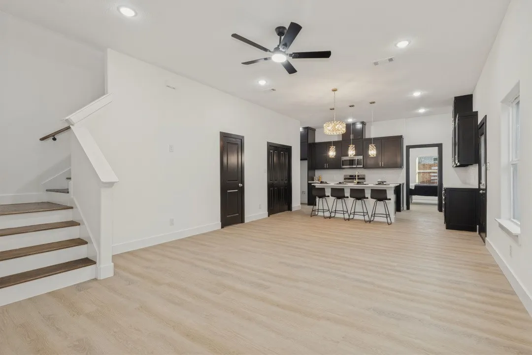 Open-concept living space with light wood-finish flooring, recessed lighting, and a modern ceiling fan