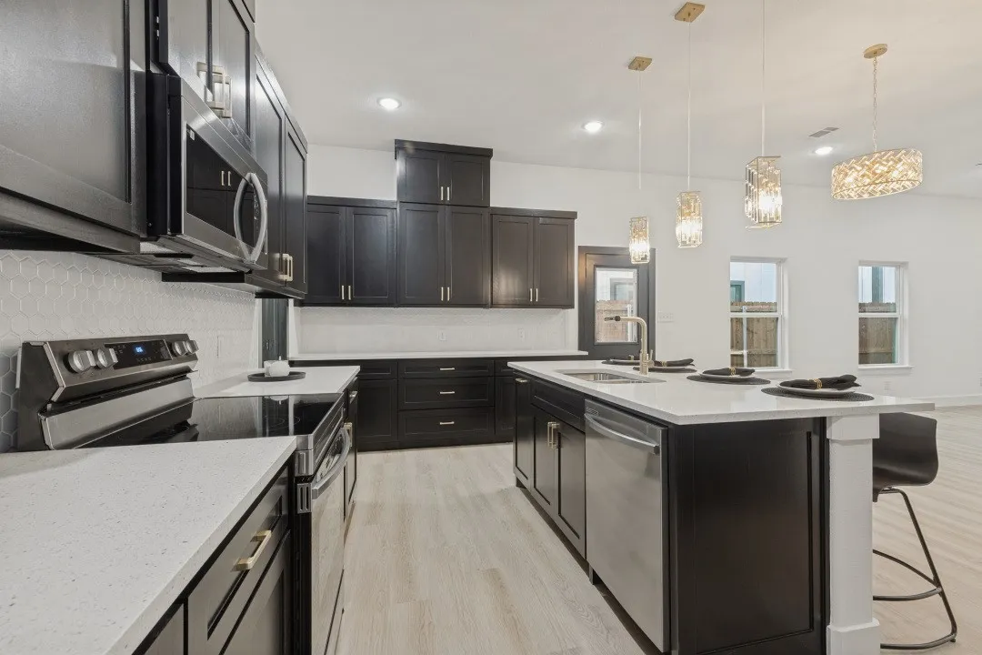 Kitchen featuring dark cabinetry, light-toned countertops, a full suite of stainless steel appliances, and wood-finish flooring