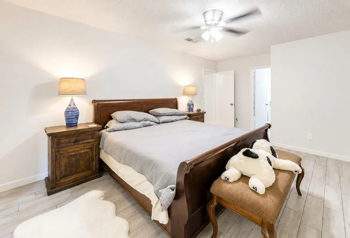 Wood-finish flooring throughout, ceiling fan with integrated lighting, and white painted walls