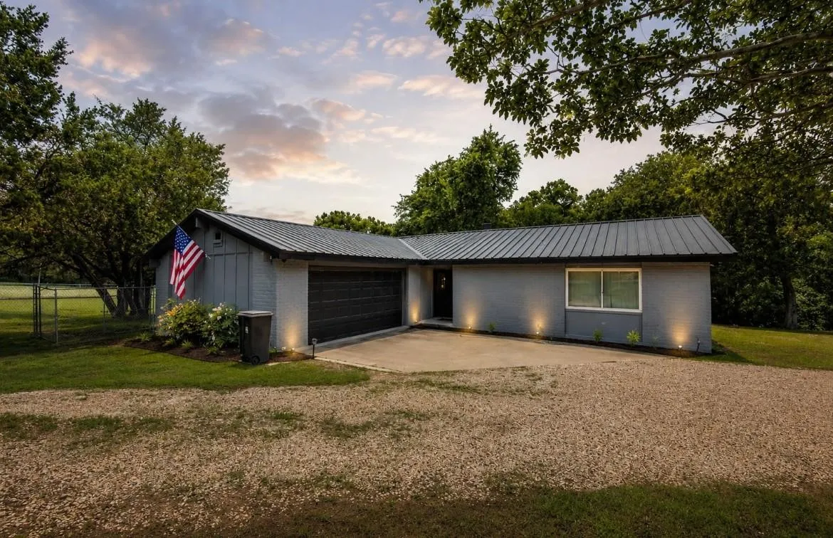 Single-story residence featuring a gray exterior, metal roof, and an attached garage with a black door