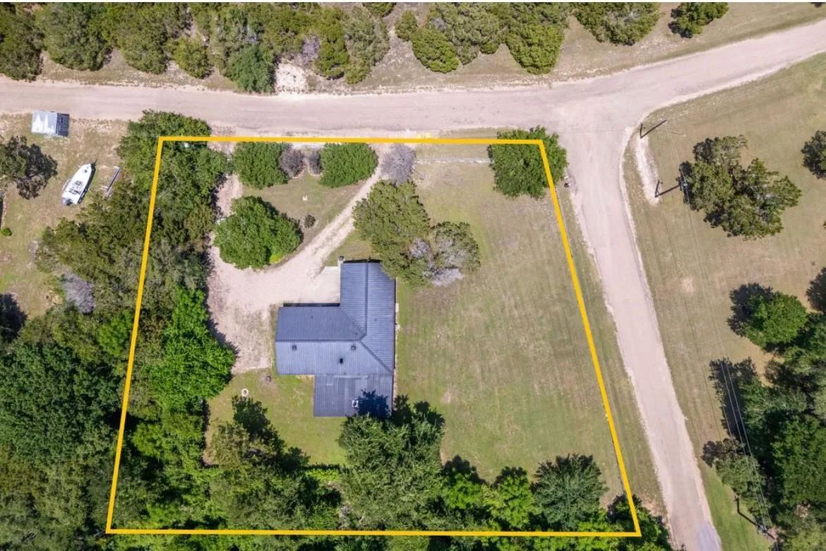 Expansive property with a dark-pitched roof structure, surrounded by mature trees and natural landscaping