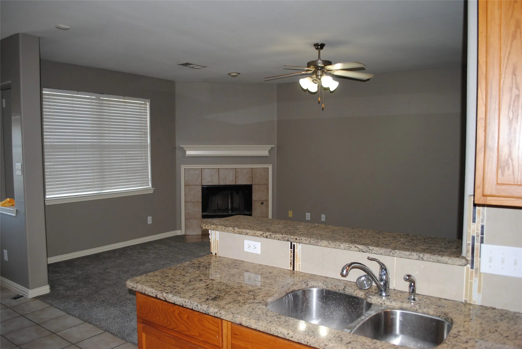 Kitchen with granite countertops, double basin stainless steel sink, and wood cabinetry