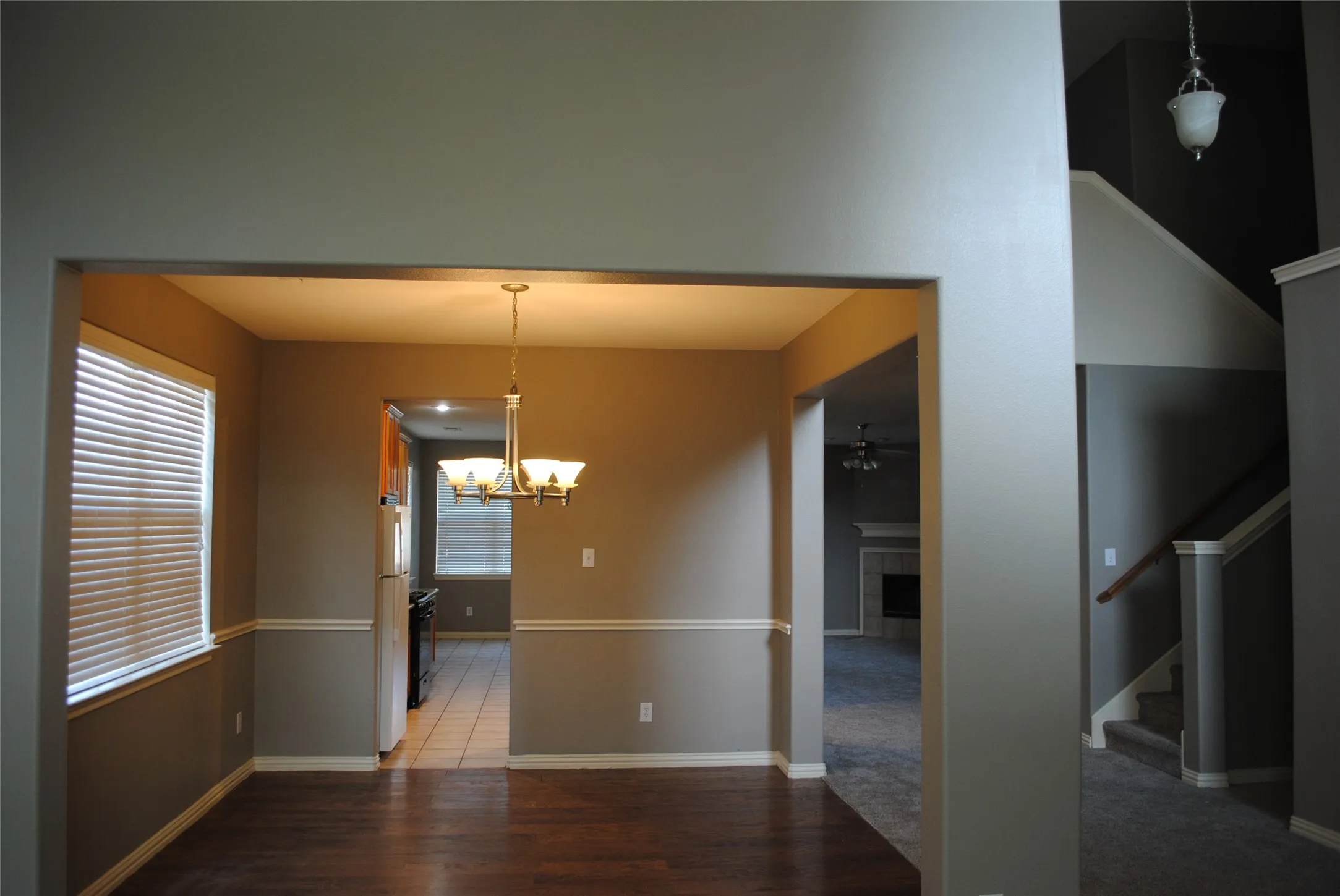 Wood-finish flooring, chair rail molding, and a chandelier illuminate the space