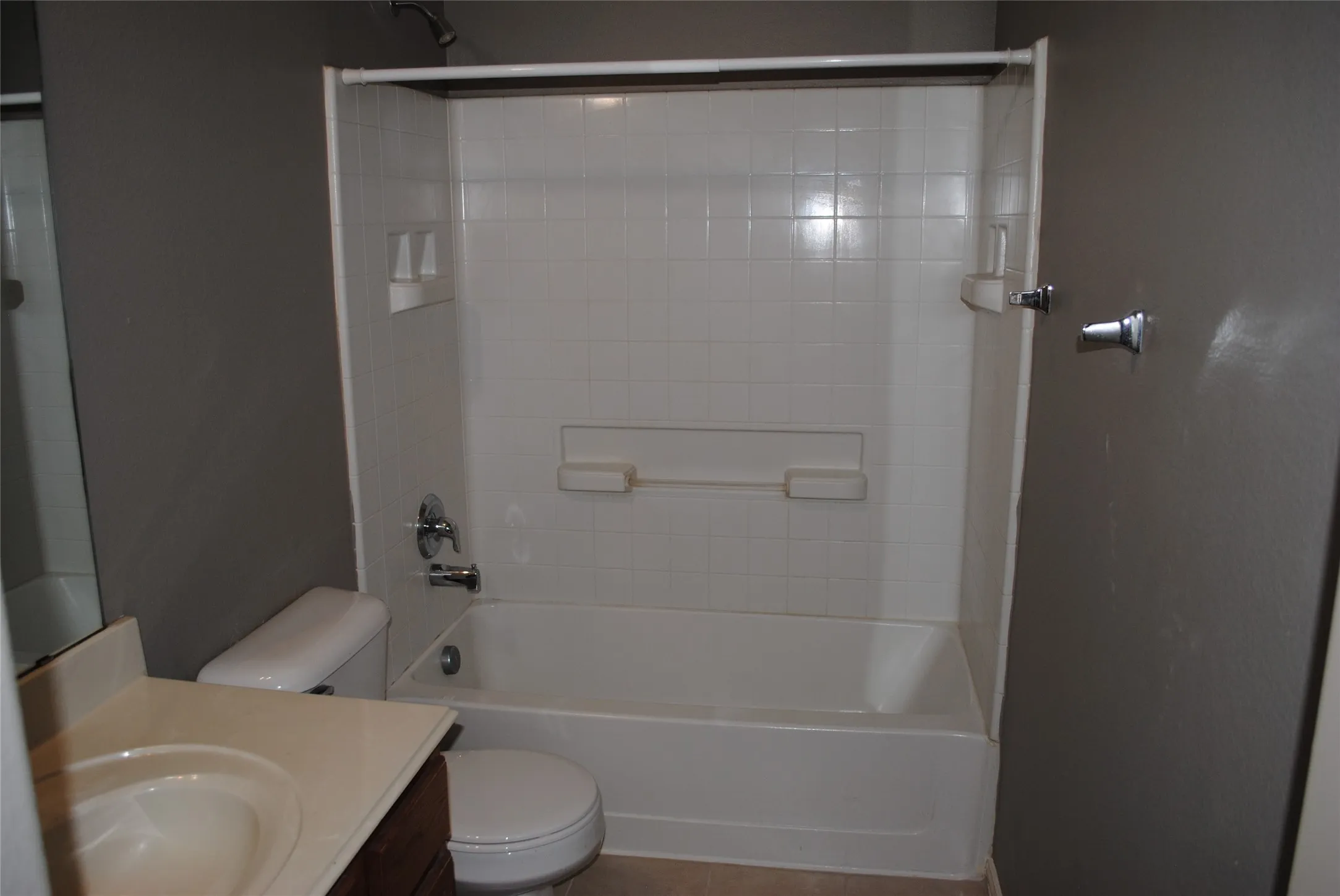 Upstairs full bath. White bathtub and shower surround with integrated shelving