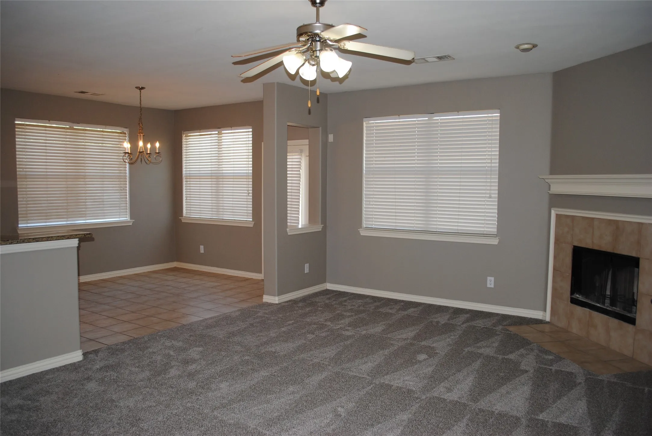 Open concept living area with a fireplace featuring a tile surround and mantel