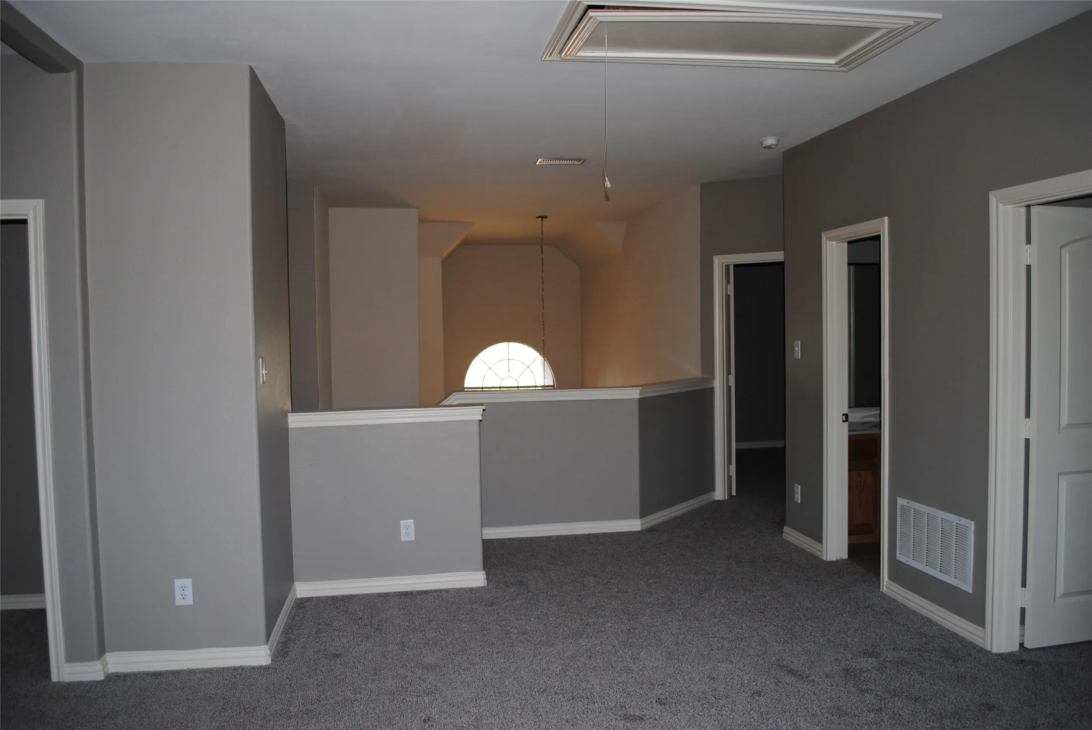 Carpeted flooring, vaulted ceiling, arched window, and multiple interior doorways