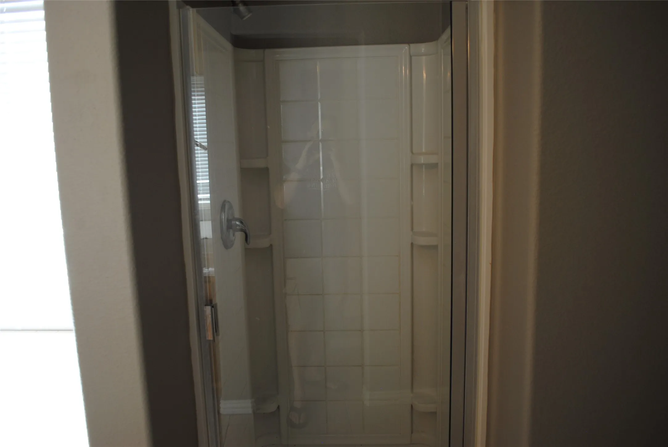 Shower enclosure with clear glass door and wall-mounted fixtures