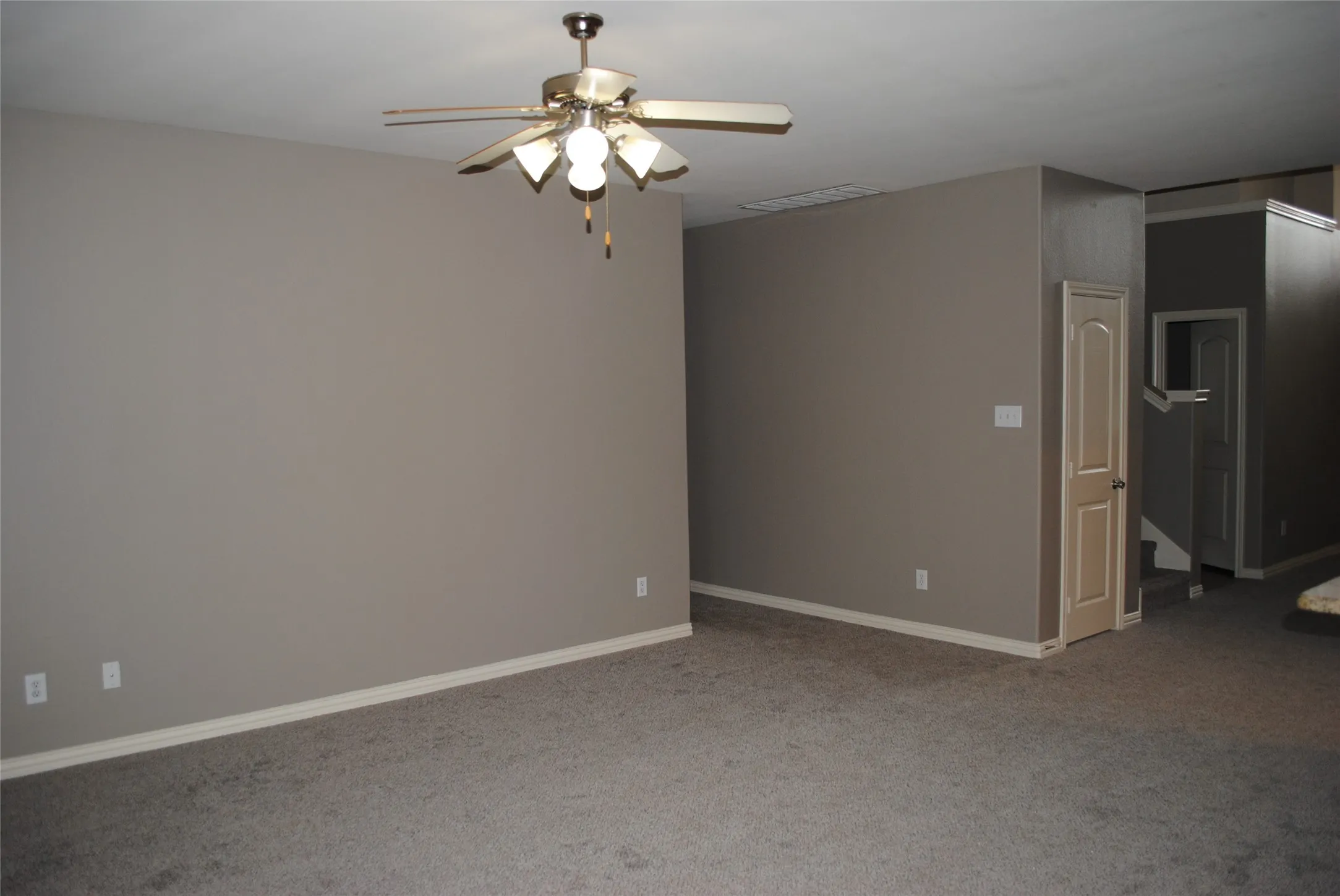 Neutral-toned carpeting, light gray wall paint, and a ceiling fan with integrated lighting