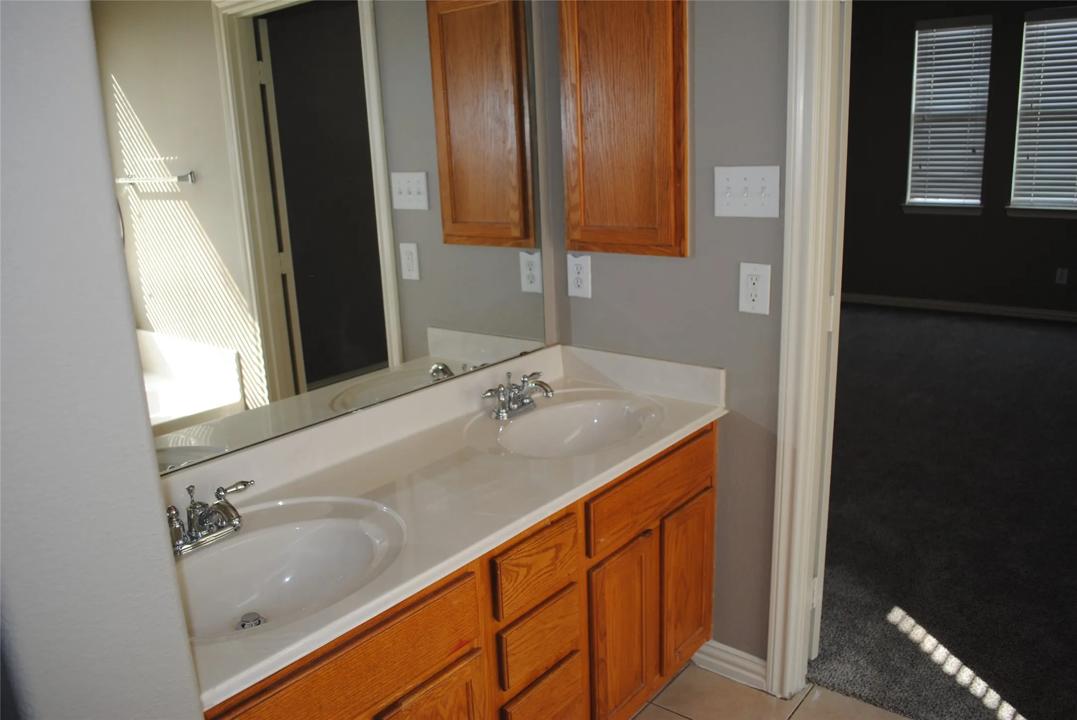 Mater bath. Double vanity with integrated sinks, wood cabinetry, and chrome fixtures