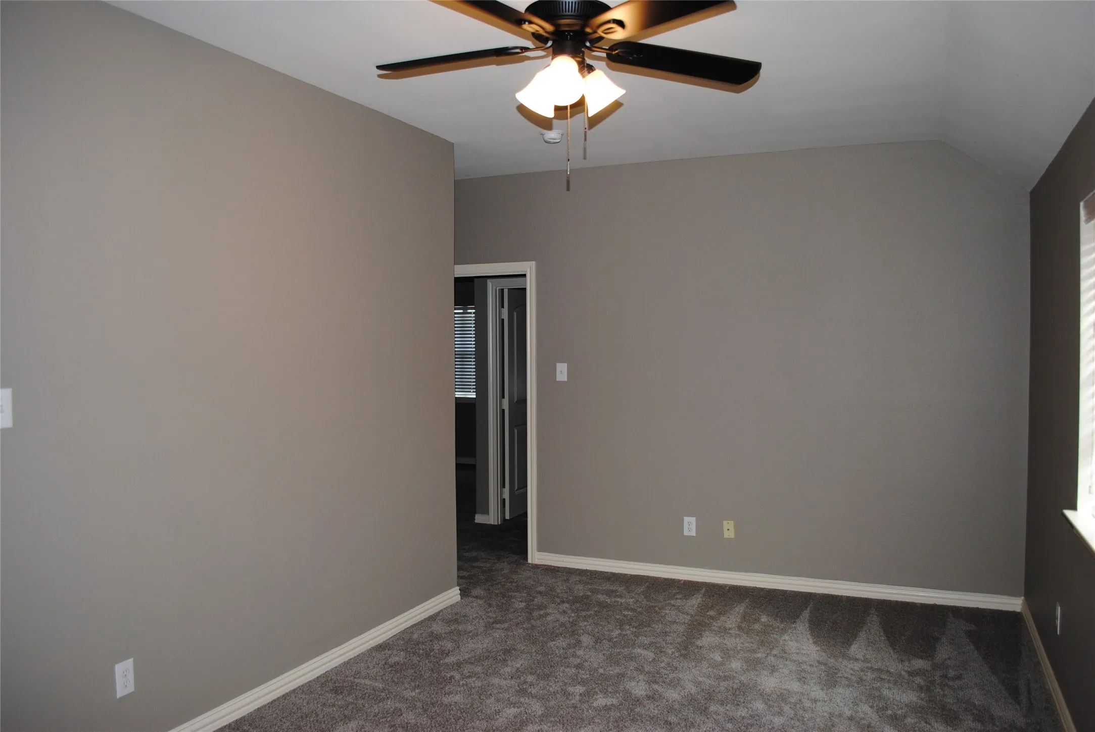 Vaulted ceiling with a ceiling fan, neutral wall tones, and carpeted flooring