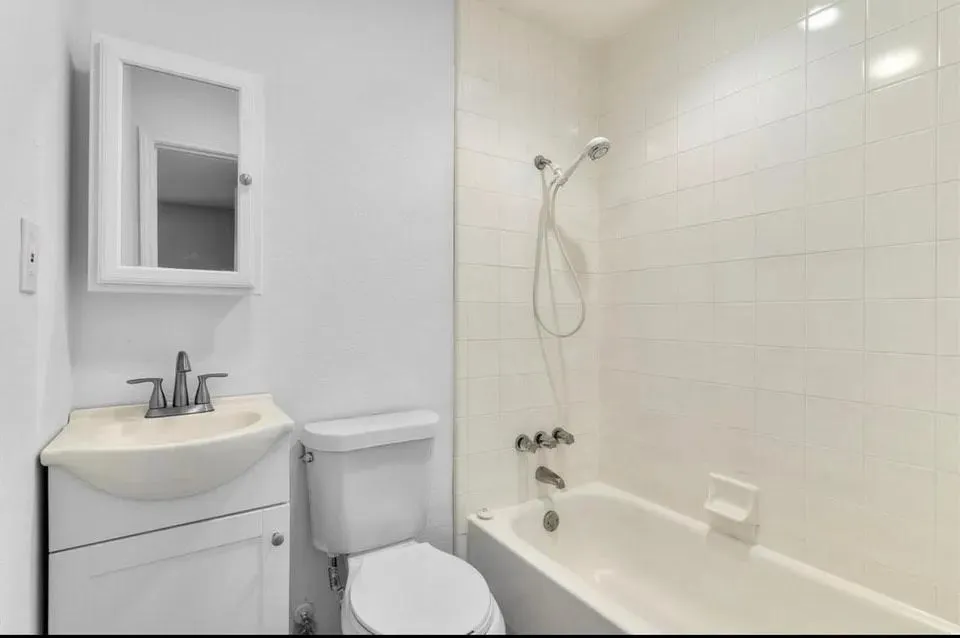 Bright bathroom showcasing an alcove tub-shower, toilet and vanity with mirror