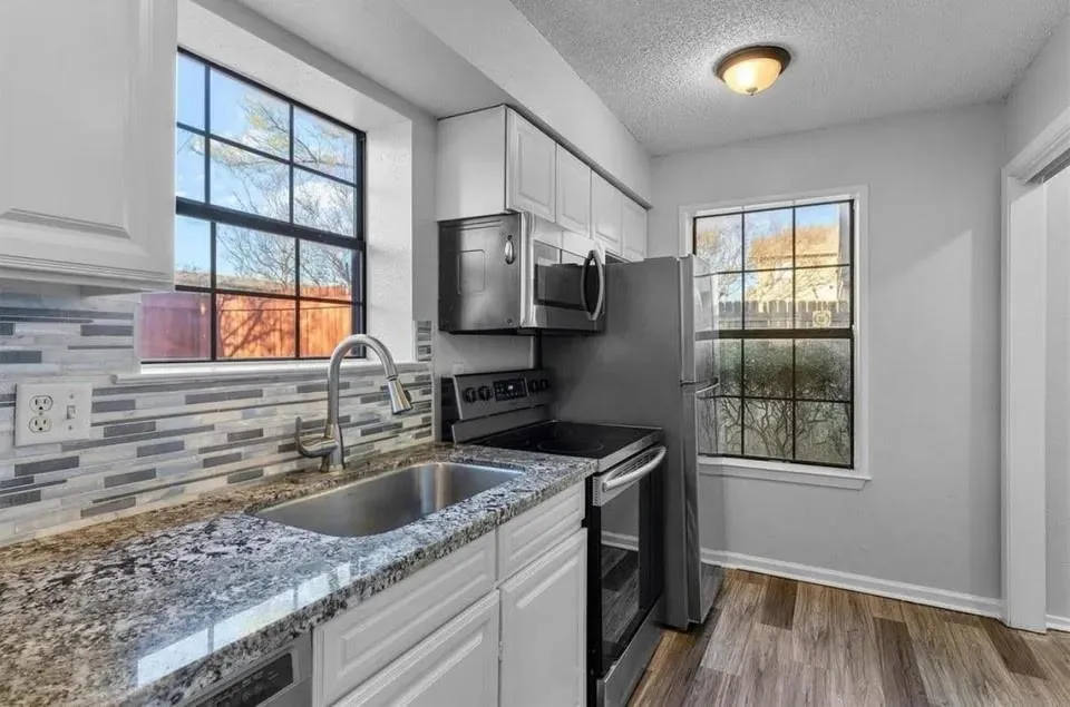 Bright kitchen showcasing stainless steel appliances, built-in cabinets and windows to let in natural light.