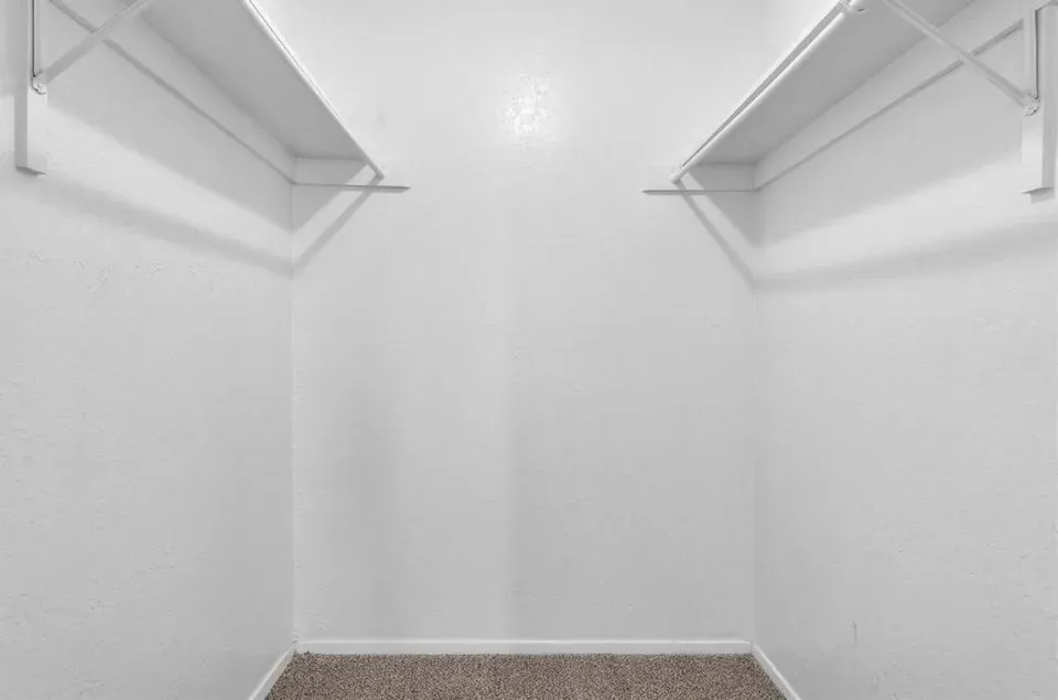 A spacious, well-kit walk-in closet featuring parallel shelves