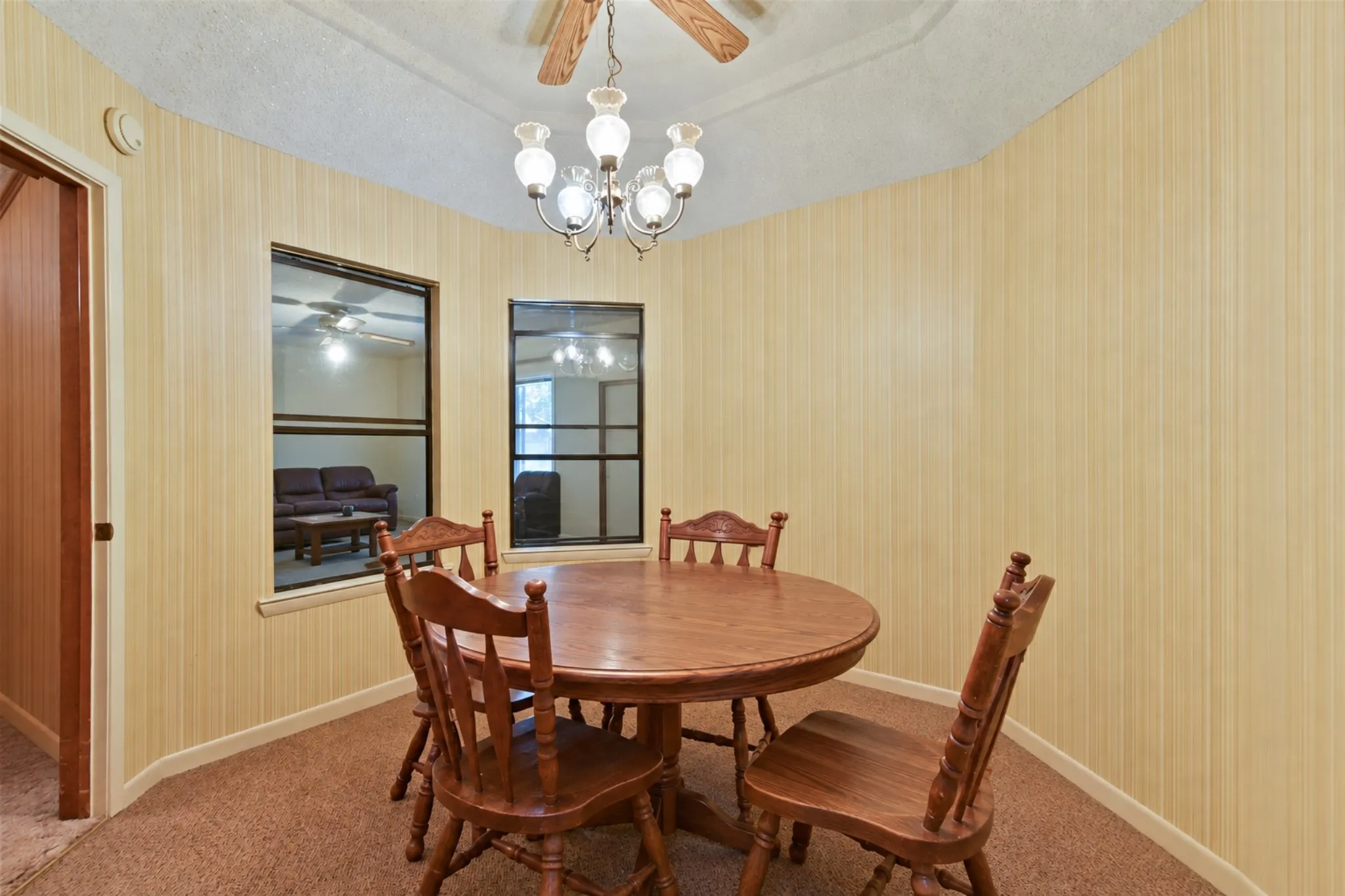 Elegant dining room showcasing warm cream-colored vertical shiplap walls, hardwood flooring, and a curved ceiling detail