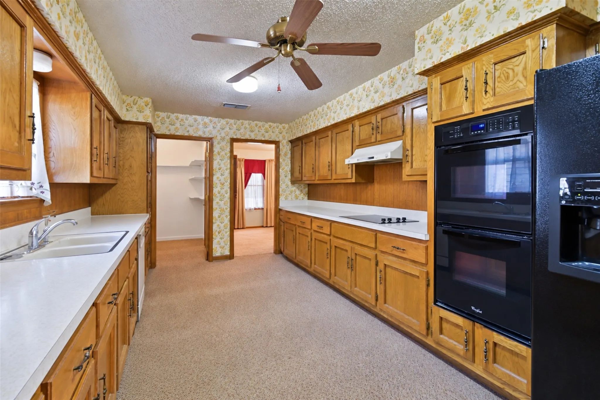 Wood cabinetry with abundant storage, white countertops, built-in double oven, and recessed lighting