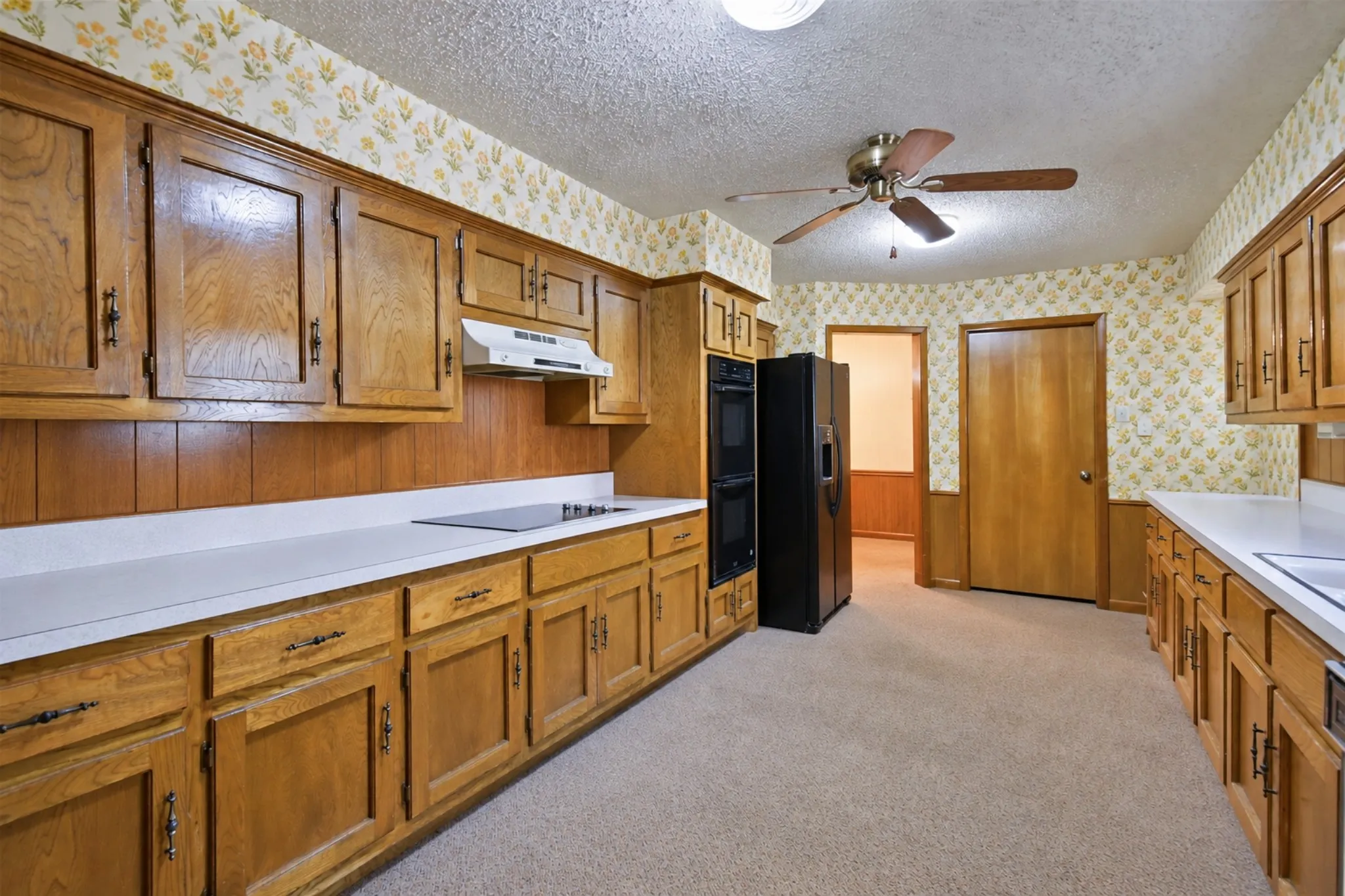 Kitchen featuring wood cabinetry, white countertops, built-in cooktop, and double wall ovens