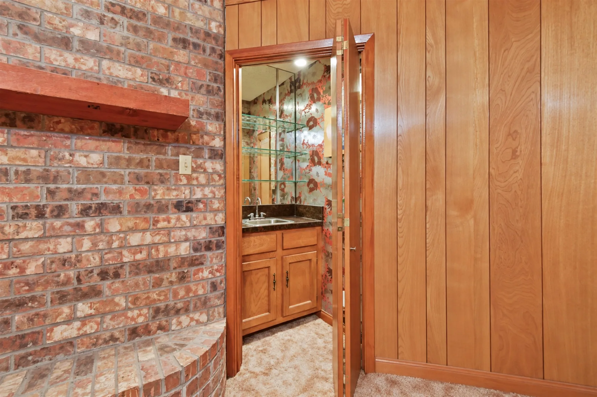Brick-clad wall with hearth, wood mantel, and vertical wood-paneled wall