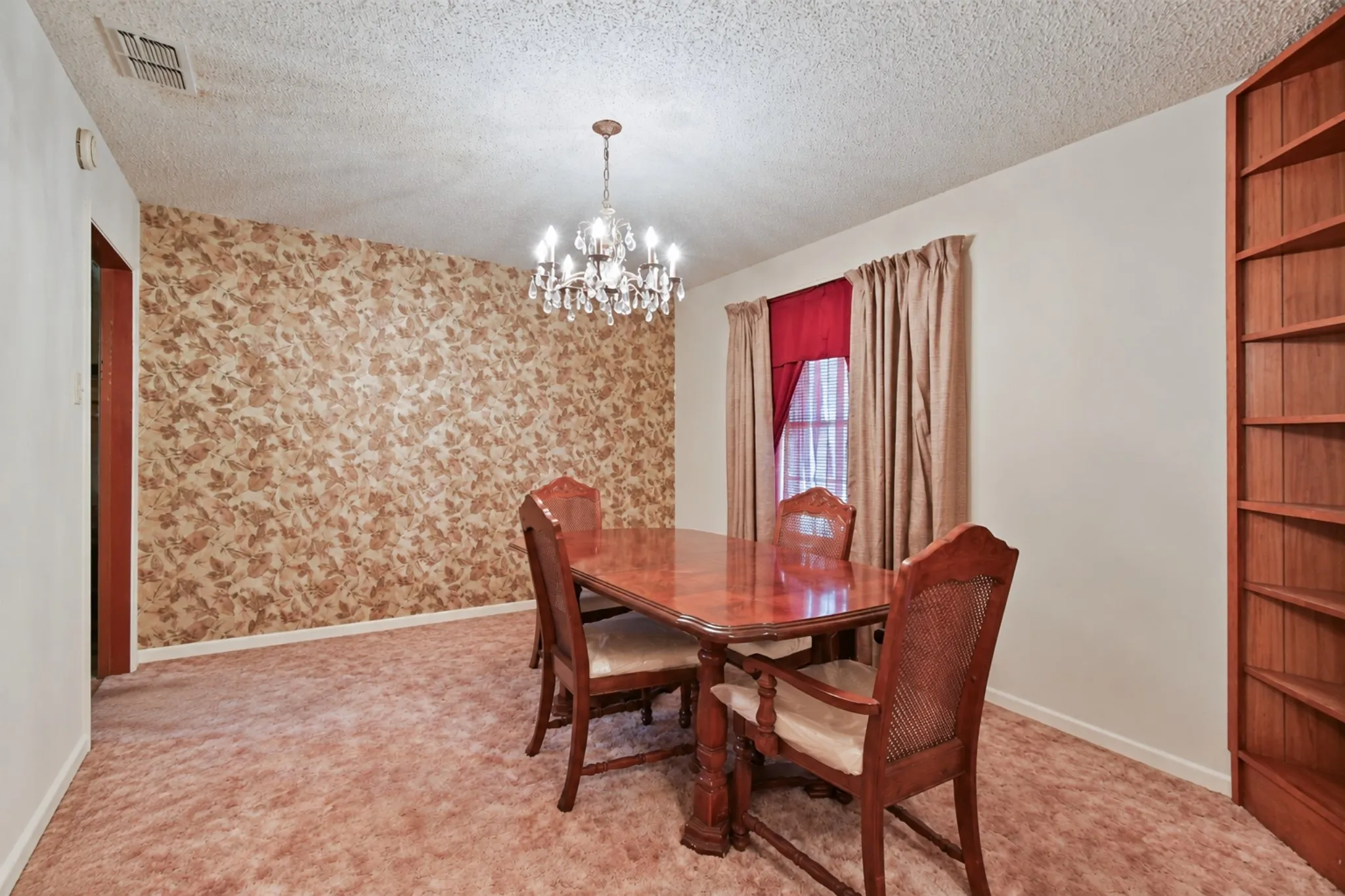 Textured wallpaper accent wall, built-in wooden shelving, and a chandelier light fixture