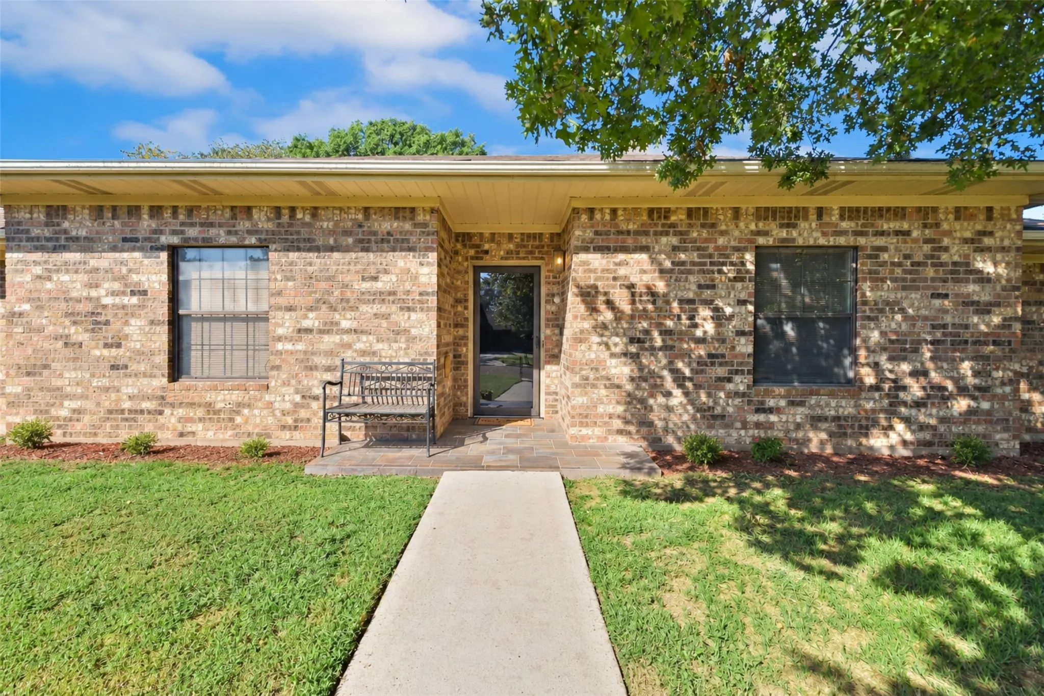 Brick exterior with a covered entry and concrete walkway