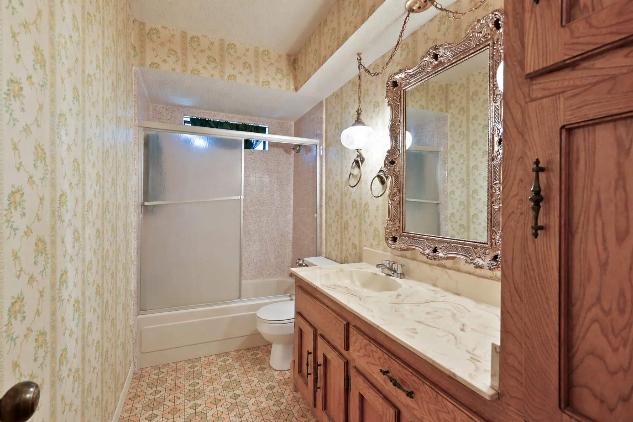 Wood-finish vanity with a single basin, light-toned countertop, and decorative framed mirror