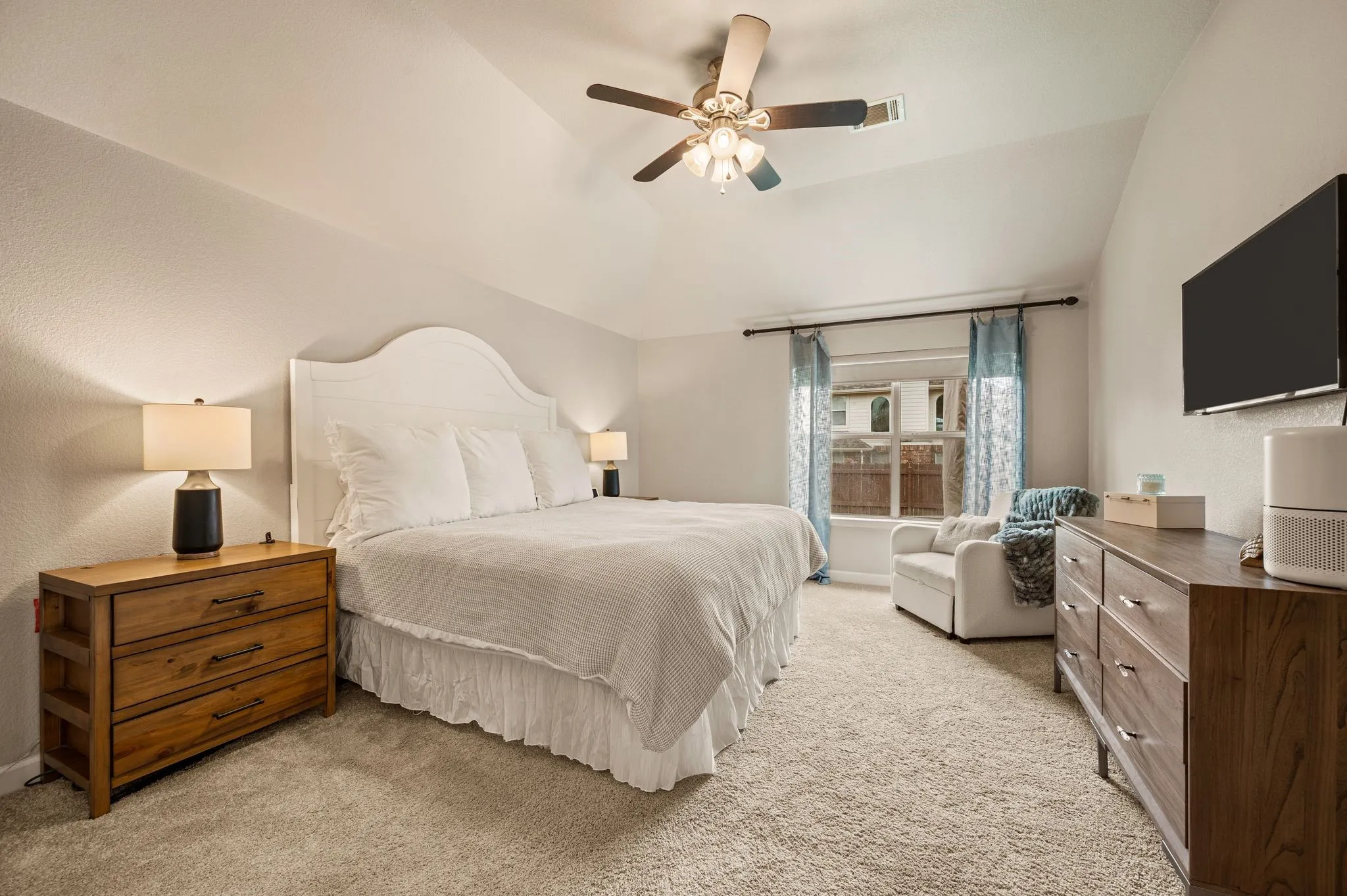 Vaulted ceiling with a ceiling fan, carpeted flooring, and a large window