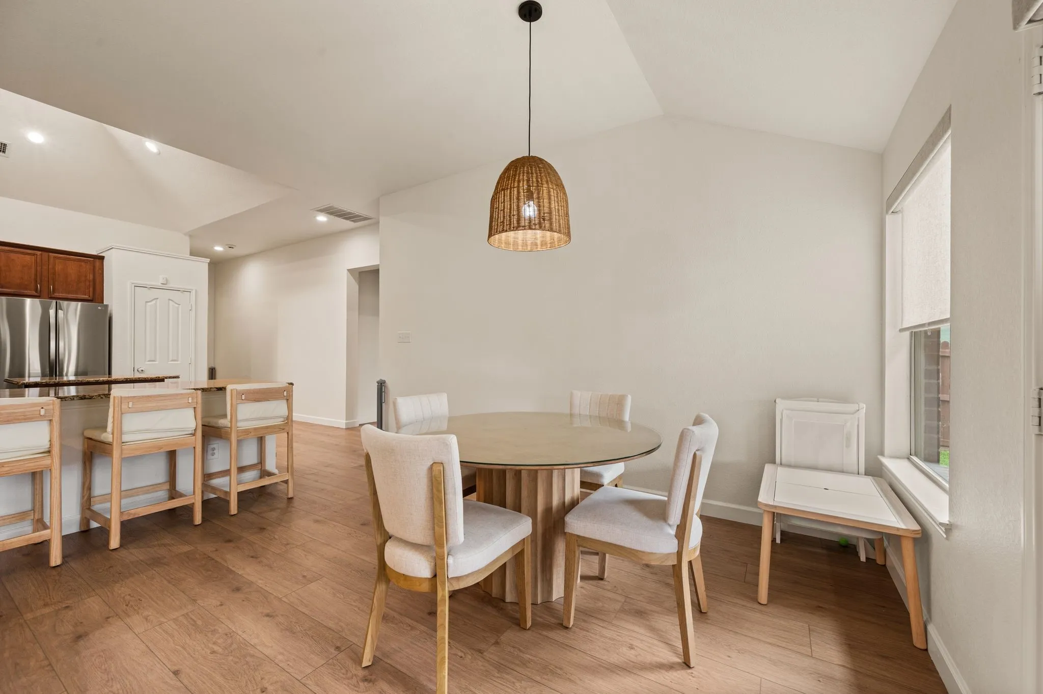 Wood-finish flooring, vaulted ceiling, recessed lighting, window with roller shade, and built-in stainless steel appliances