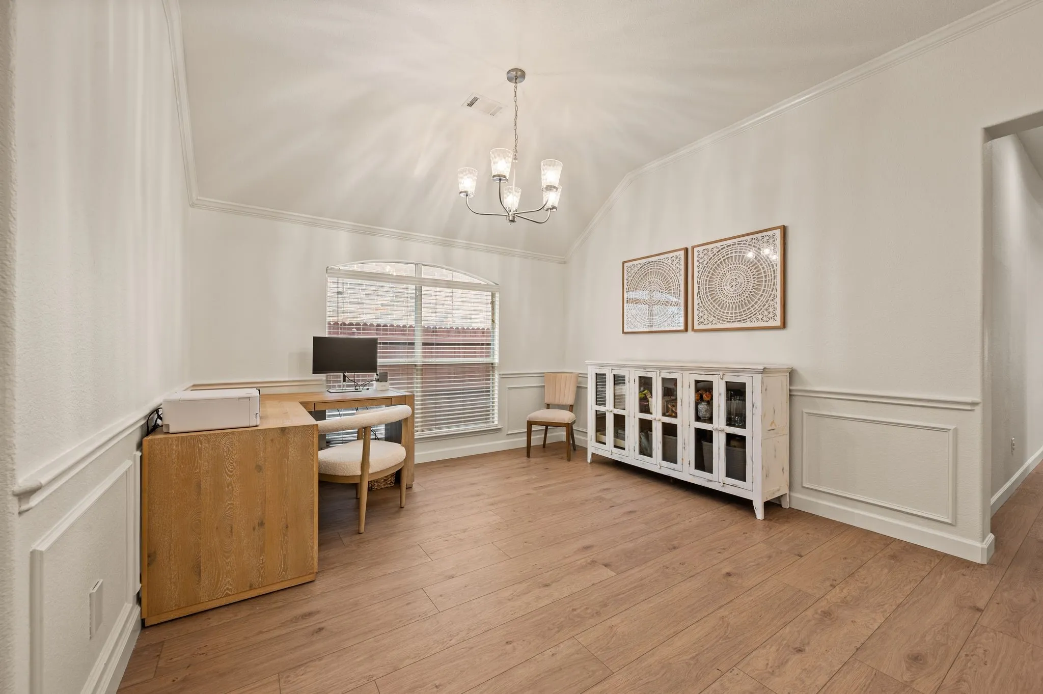 Vaulted ceiling, wood-finish flooring, arched window, chandelier, and wainscoting