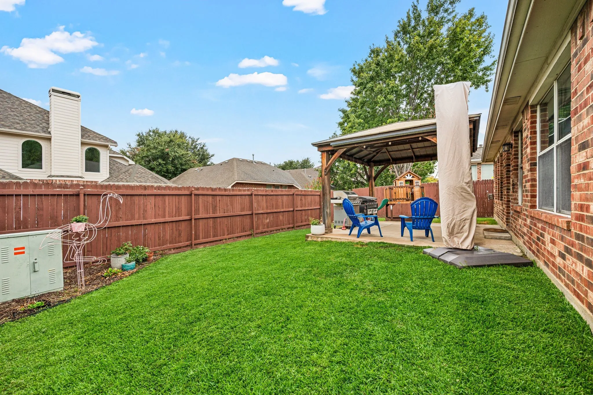 Expansive lawn area, private wood fencing, and a concrete patio with a built-in pergola
