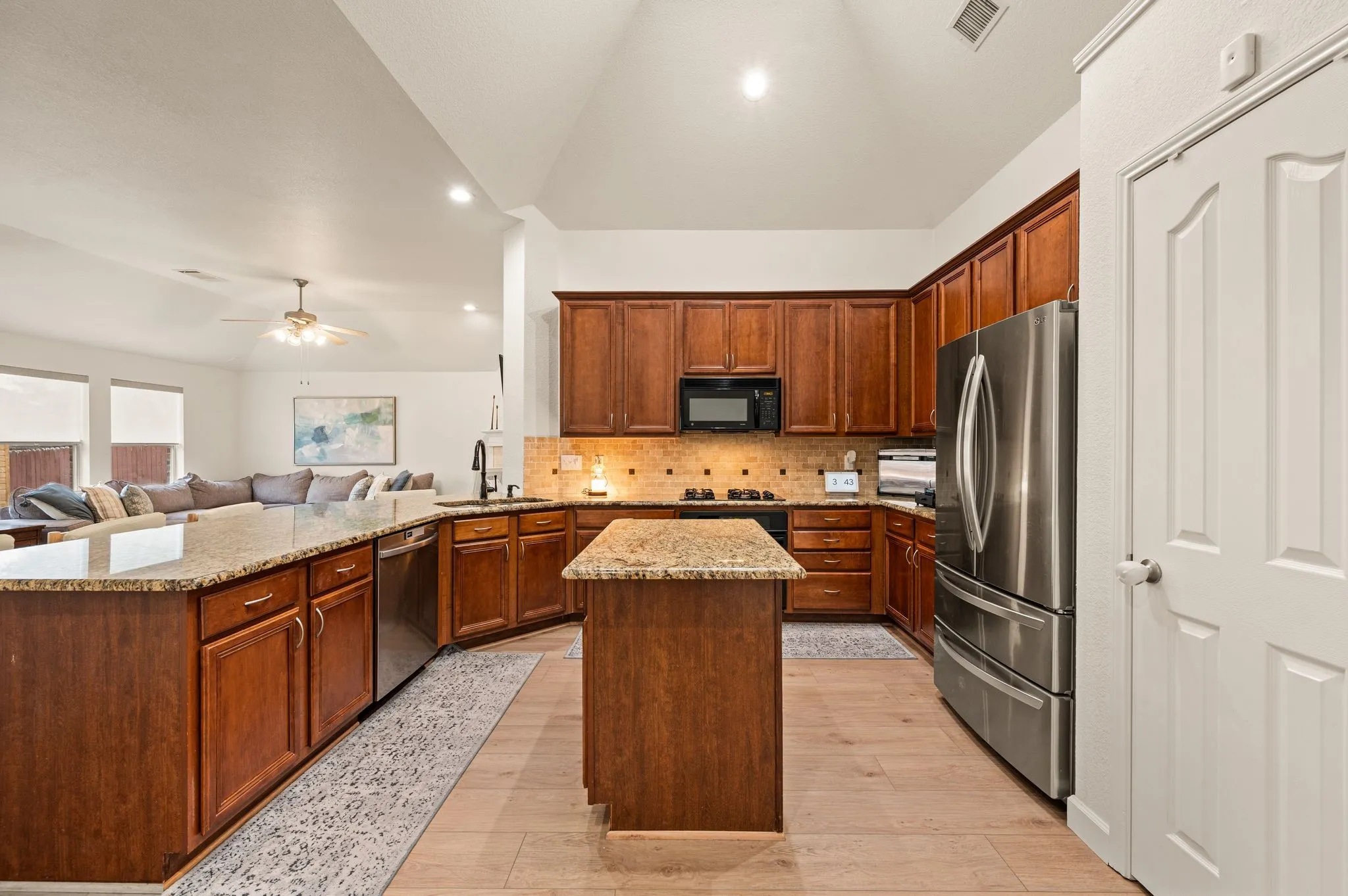 Kitchen featuring wood-finish flooring, granite countertops, wood cabinetry, and stainless steel appliances