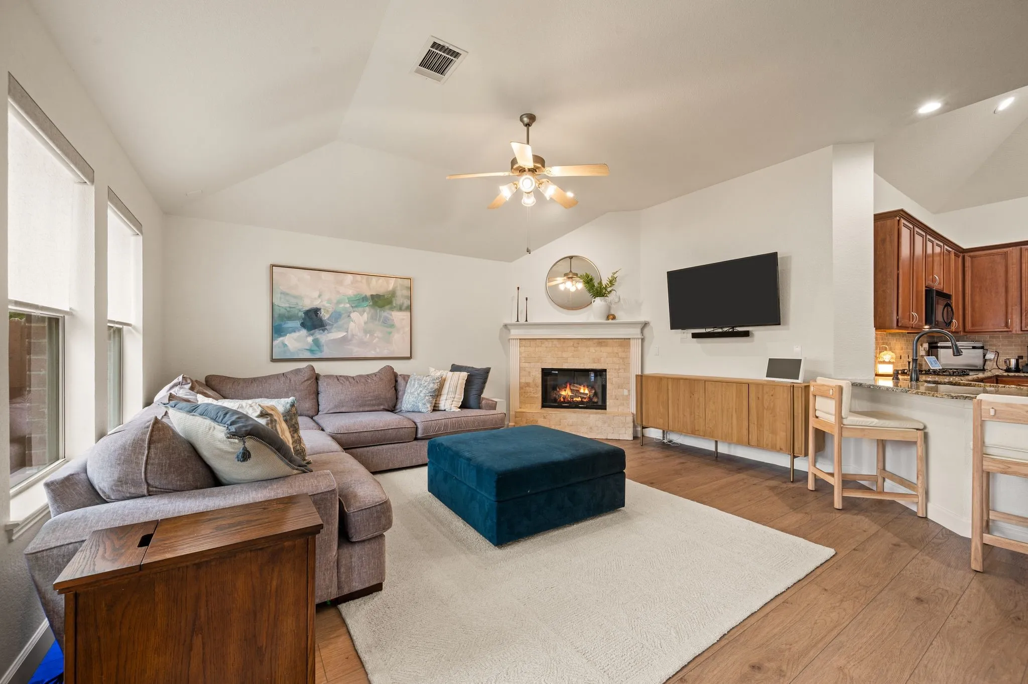 Vaulted ceilings, wood-finish flooring, and a fireplace with a stone surround