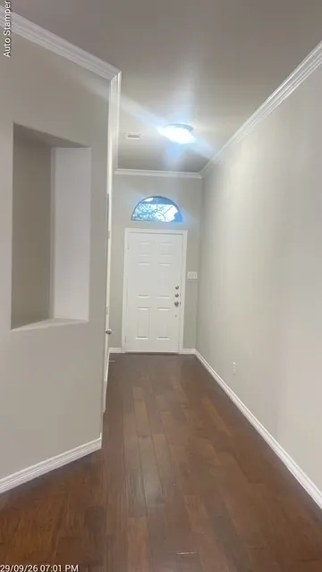 Entryway featuring wood-finish flooring, a white paneled door with an arched transom, and crown molding