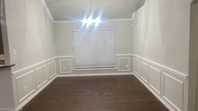 Vaulted ceiling with crown molding, wood-finish flooring, accent wainscoting, and a window with blinds