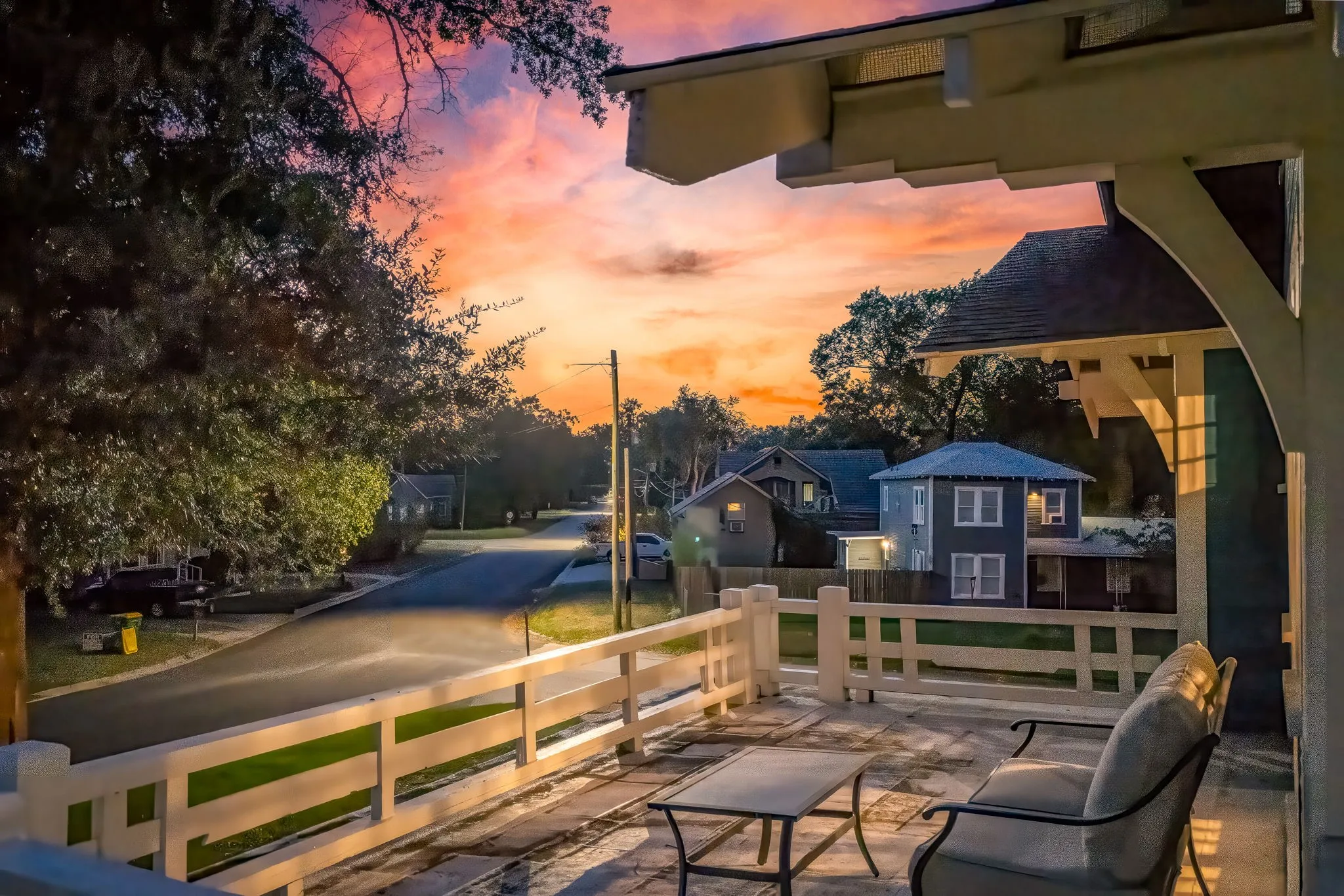 Expansive covered porch featuring a painted wood railing, concrete flooring, and exposed architectural beams