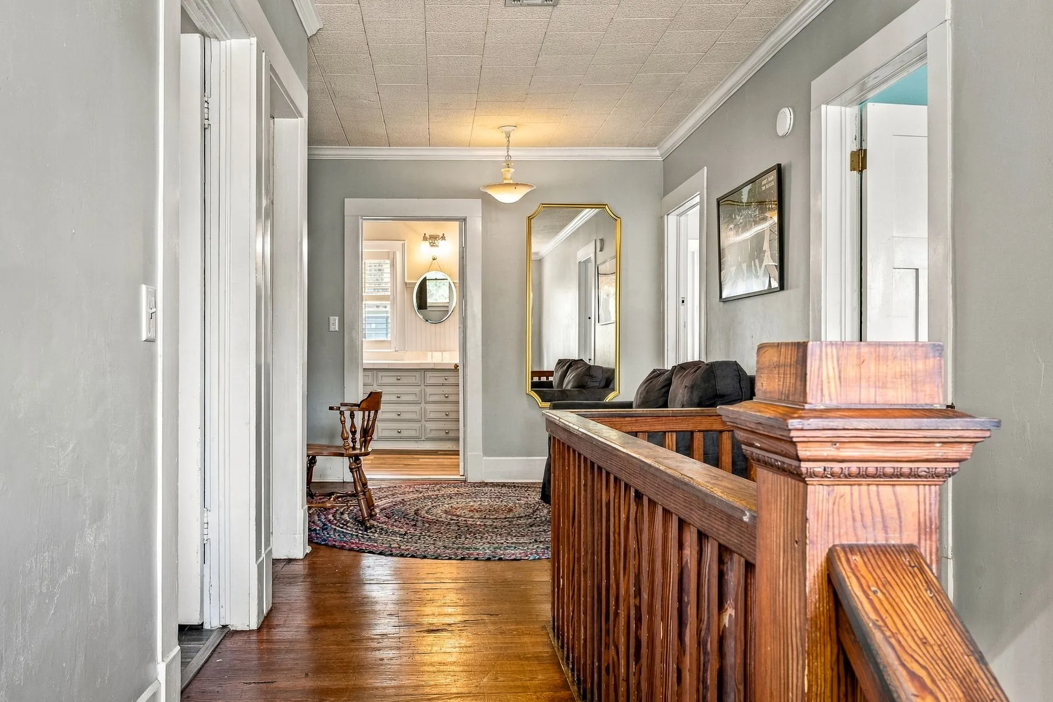Hardwood flooring, wood staircase with substantial newel post, crown molding, and a built-in vanity with dual sinks