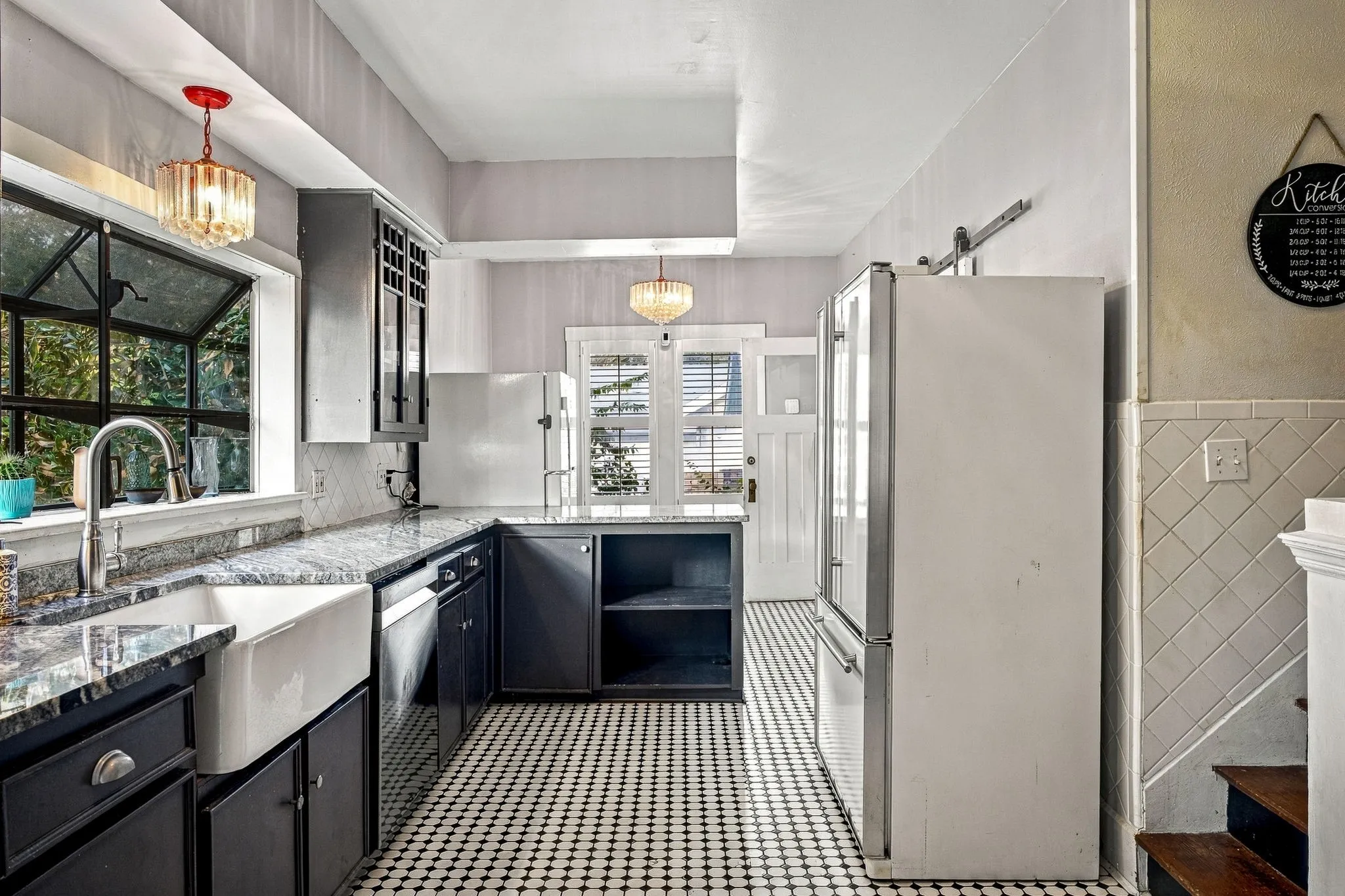 Kitchen featuring black and white mosaic tile flooring, dark cabinetry, and stone countertops