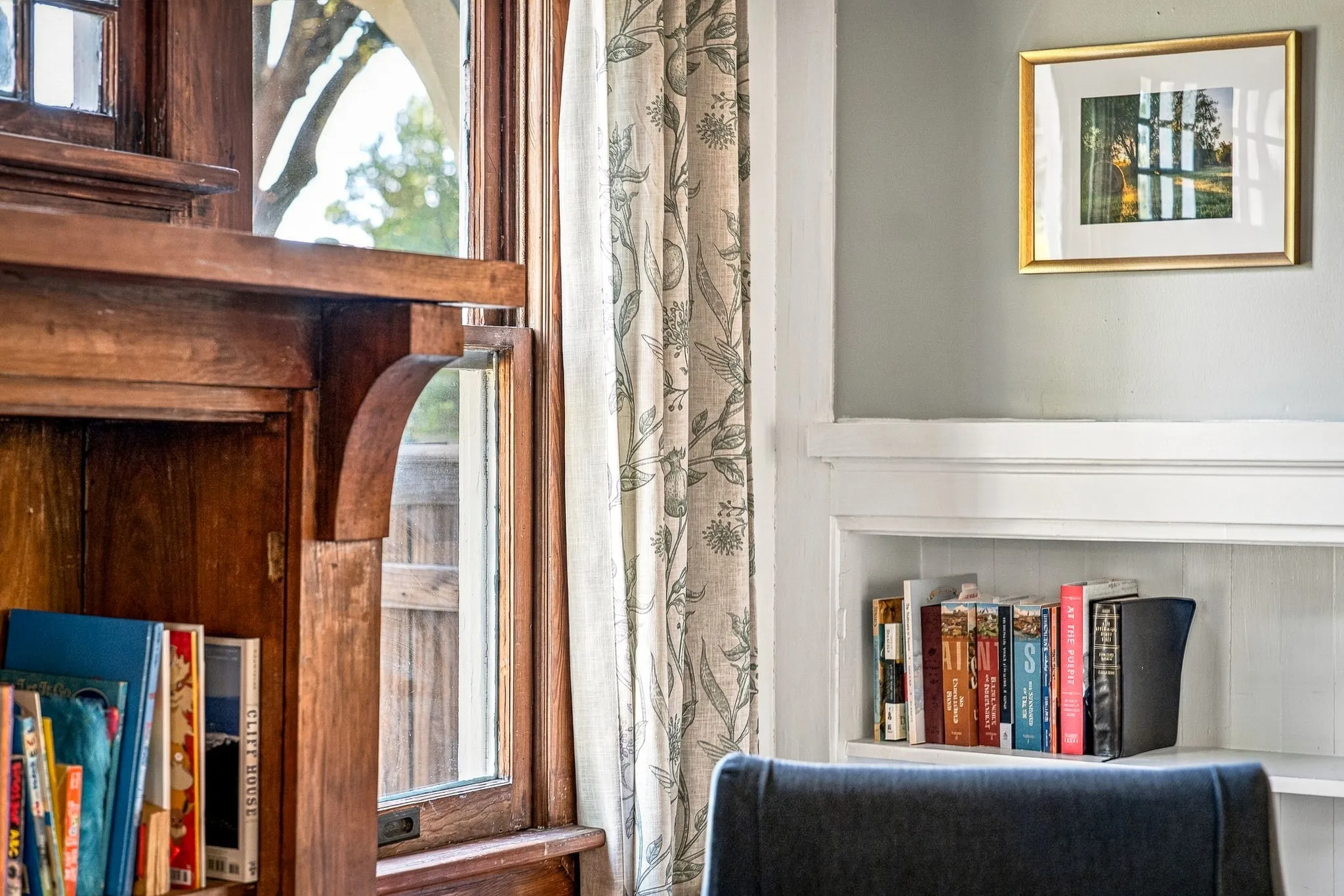 Warm wood-finish cabinetry with glass-front upper shelving, white wainscoting, and built-in bookshelves create a refined study or library space