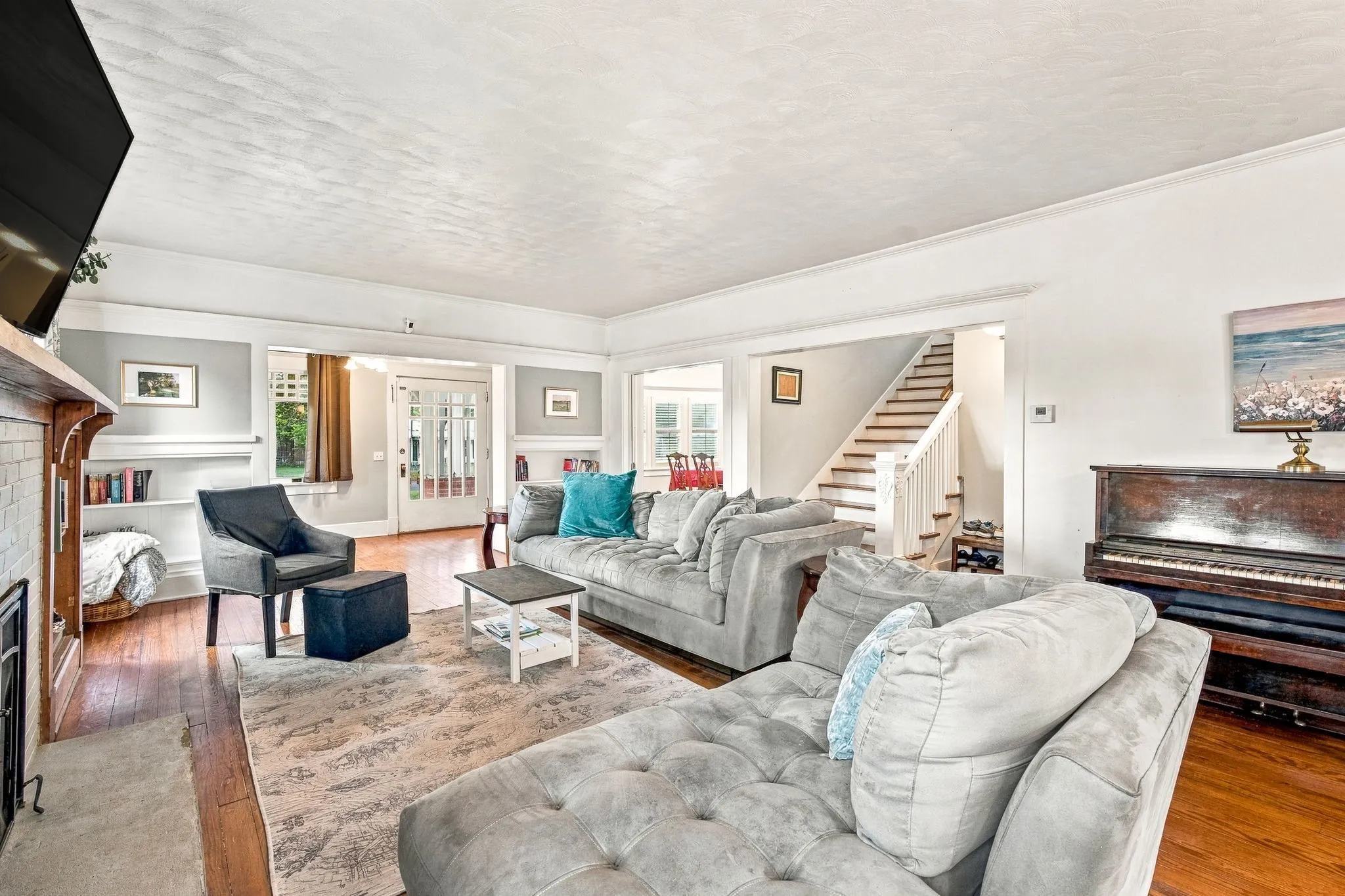 Hardwood flooring, white painted trim, built-in shelving, and a fireplace with a tile surround
