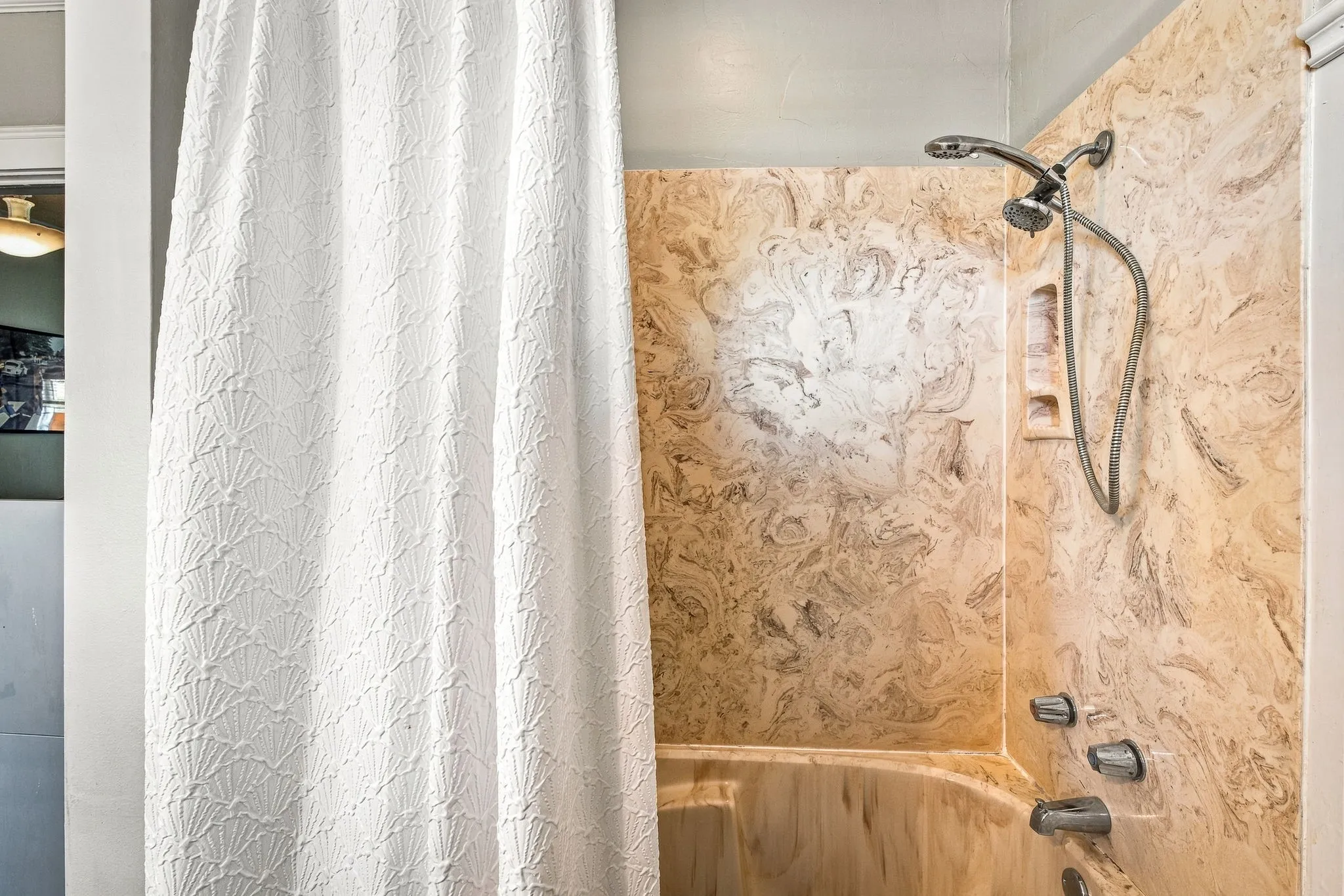 Bathtub with integrated shower, featuring a multi-function showerhead, built-in soap dish, and chrome fixtures