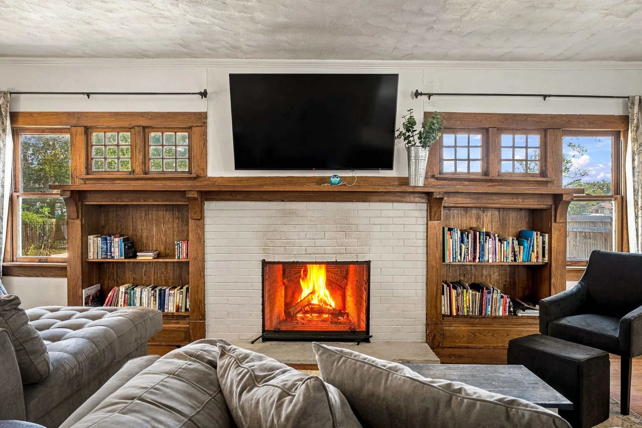 Fireplace with white brick surround, wood mantel, and integrated wood built-in shelving