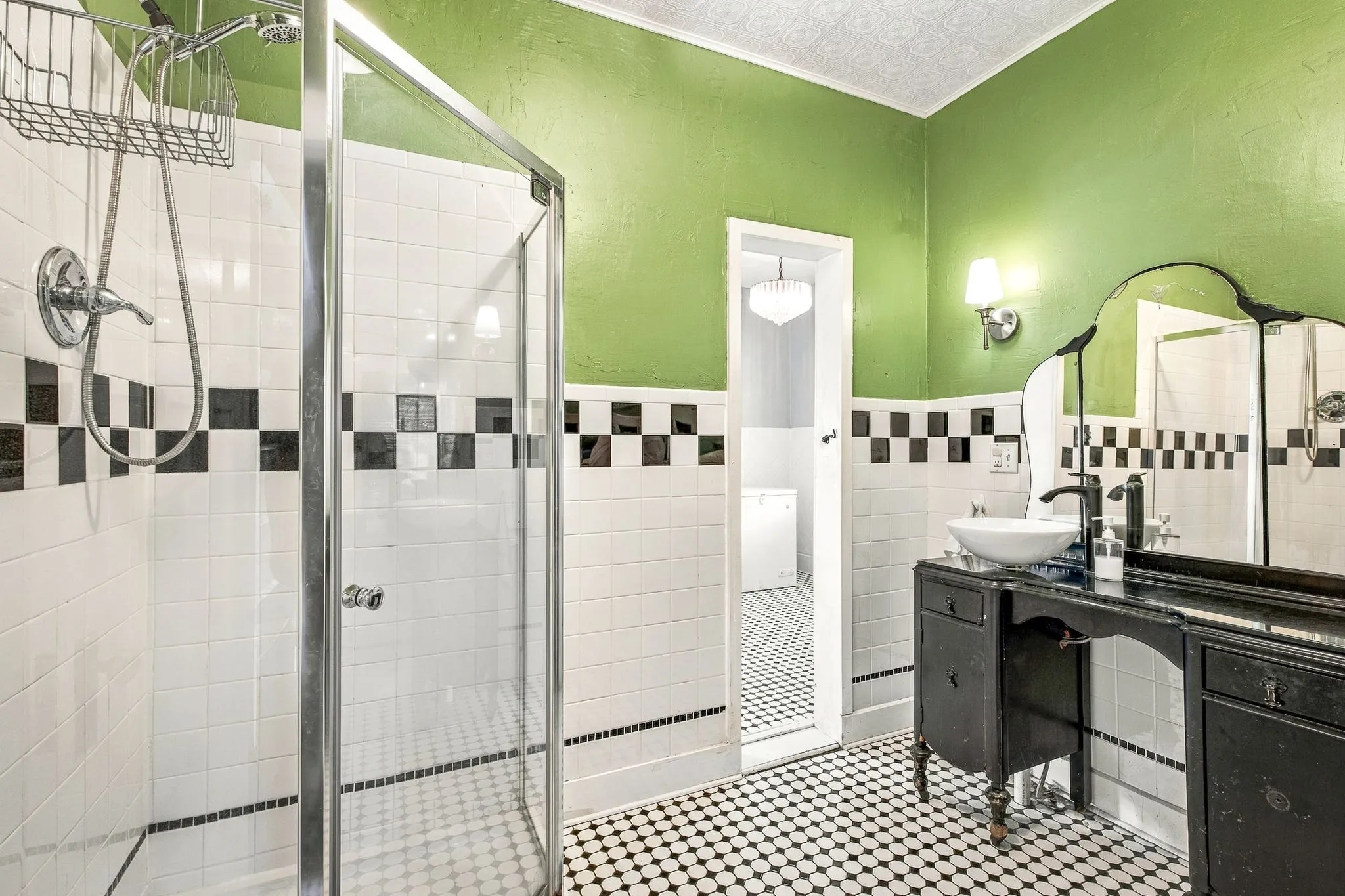Glass-enclosed shower with ceramic tile surround, checkerboard accent tiling, pedestal sink, wall-mounted sconce lighting, and decorative ceiling