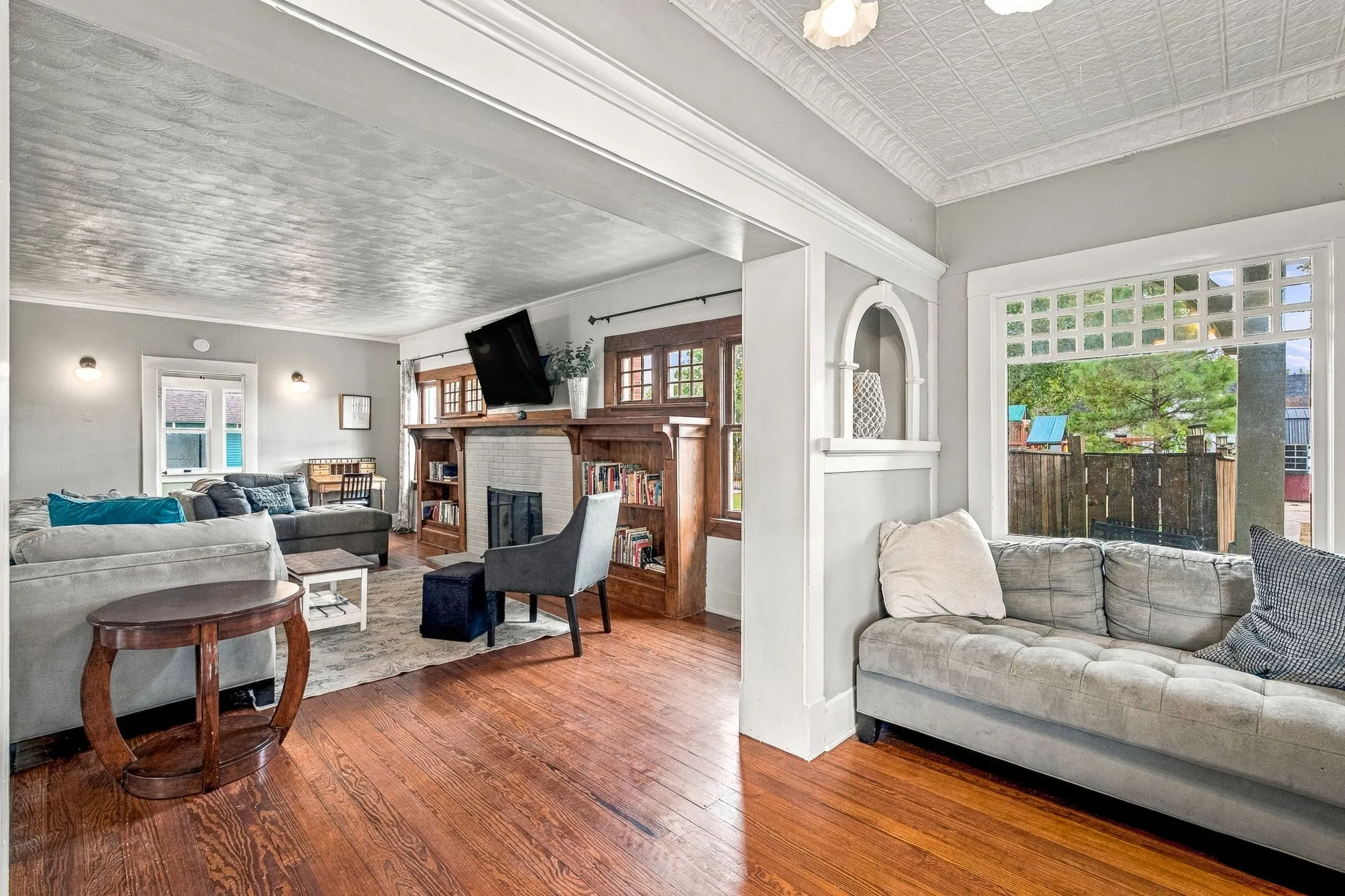 Hardwood flooring, decorative ceiling, built-in shelving, fireplace with tile surround, and arched wall niche