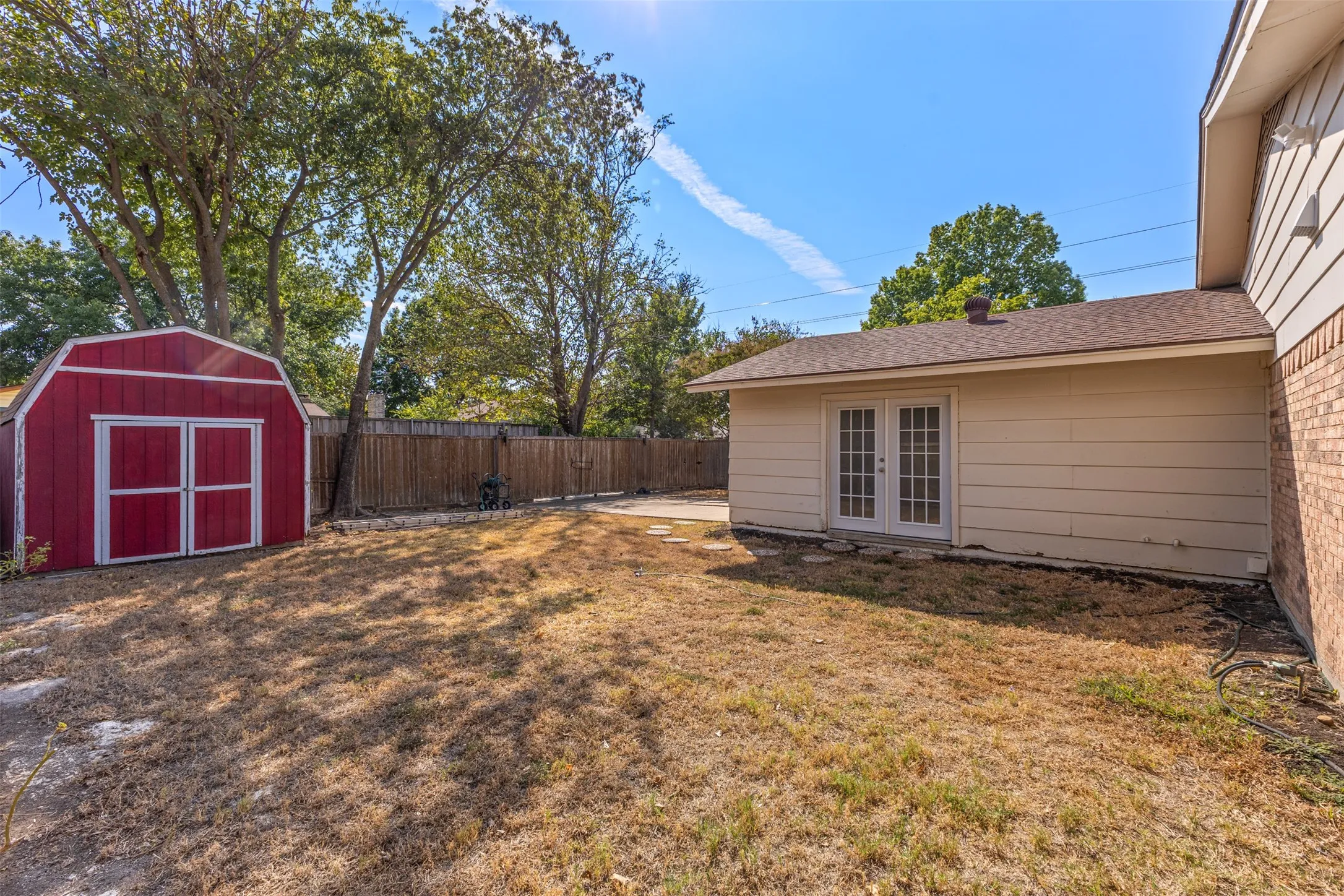 Red storage shed, wood privacy fence, double pane French doors, brick and siding exterior