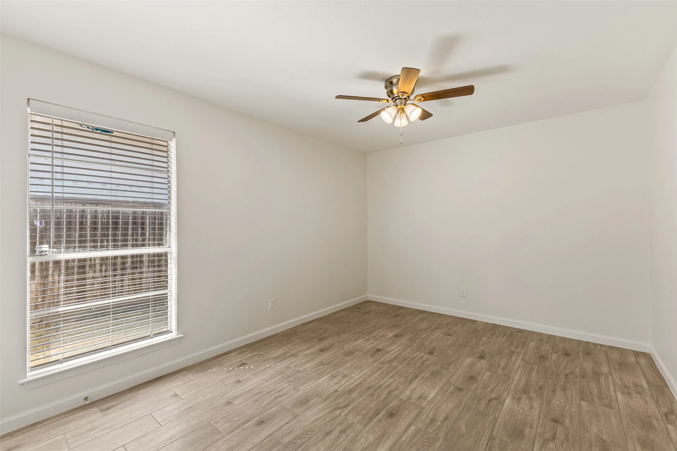 Window with blinds, wood-finish flooring, and a ceiling fan with integrated lighting