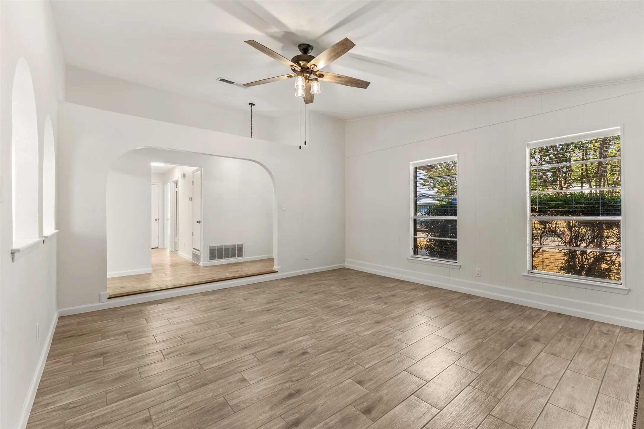 Wood-finish flooring throughout, with an arched doorway leading to an interior hallway