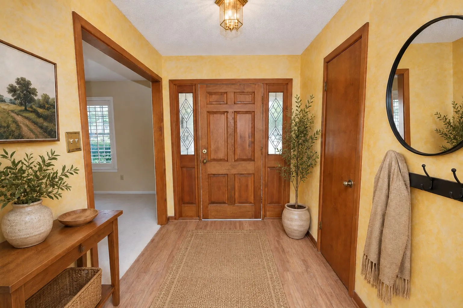Wood-finish flooring with a wood paneled door featuring decorative glass sidelights