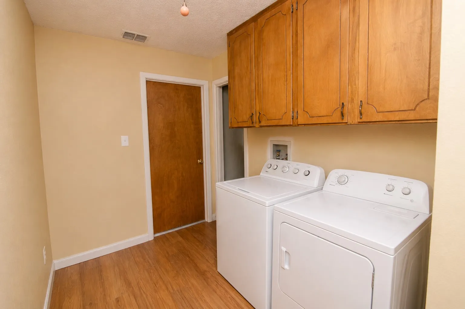 Built-in wood cabinetry with decorative hardware, wood-finish flooring, and light-toned walls