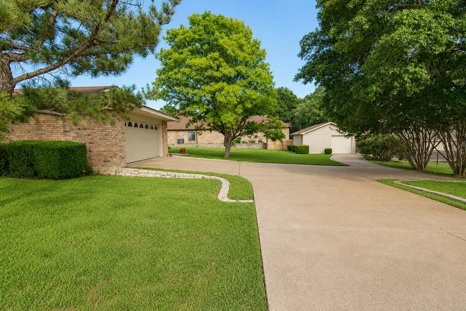 Concrete driveway with a stone-edged garden bed and brick facade