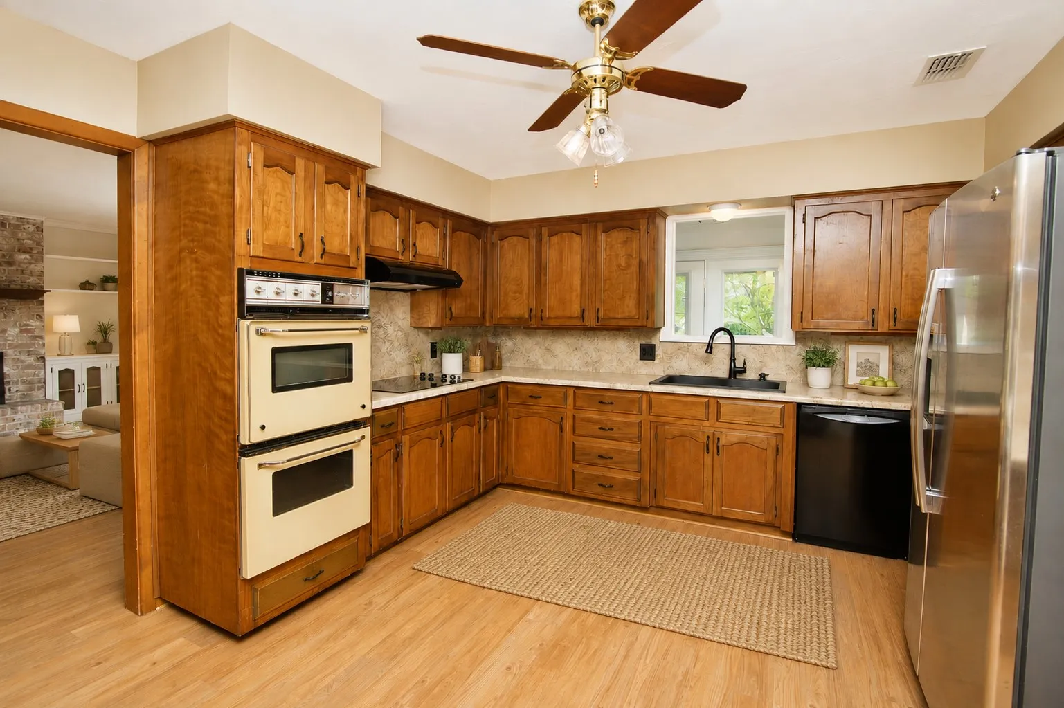 Kitchen featuring wood-finish flooring, wood cabinetry, a double wall oven, a built-in cooktop, and a stainless steel refrigerator