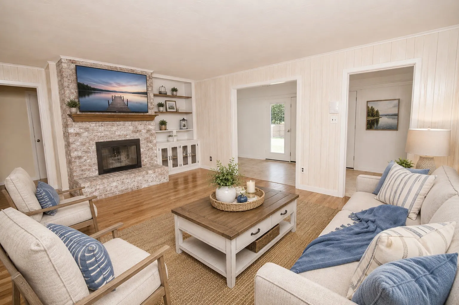 Brick fireplace with wood mantel, built-in shelving, wood-finish flooring, and paneling on walls