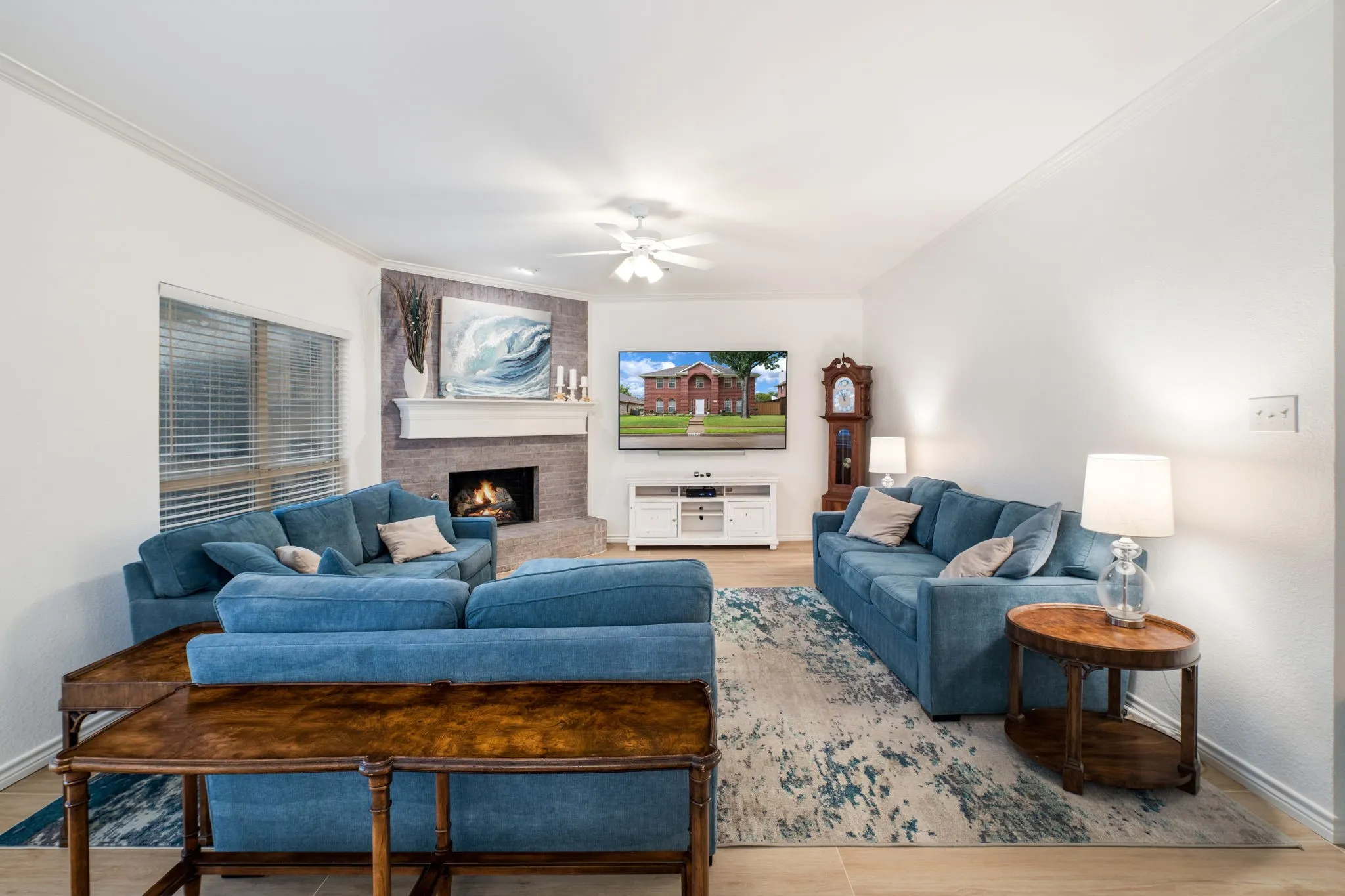 Recessed lighting, crown molding, a corner fireplace with stone surround, a white mantel, and wood-finish flooring